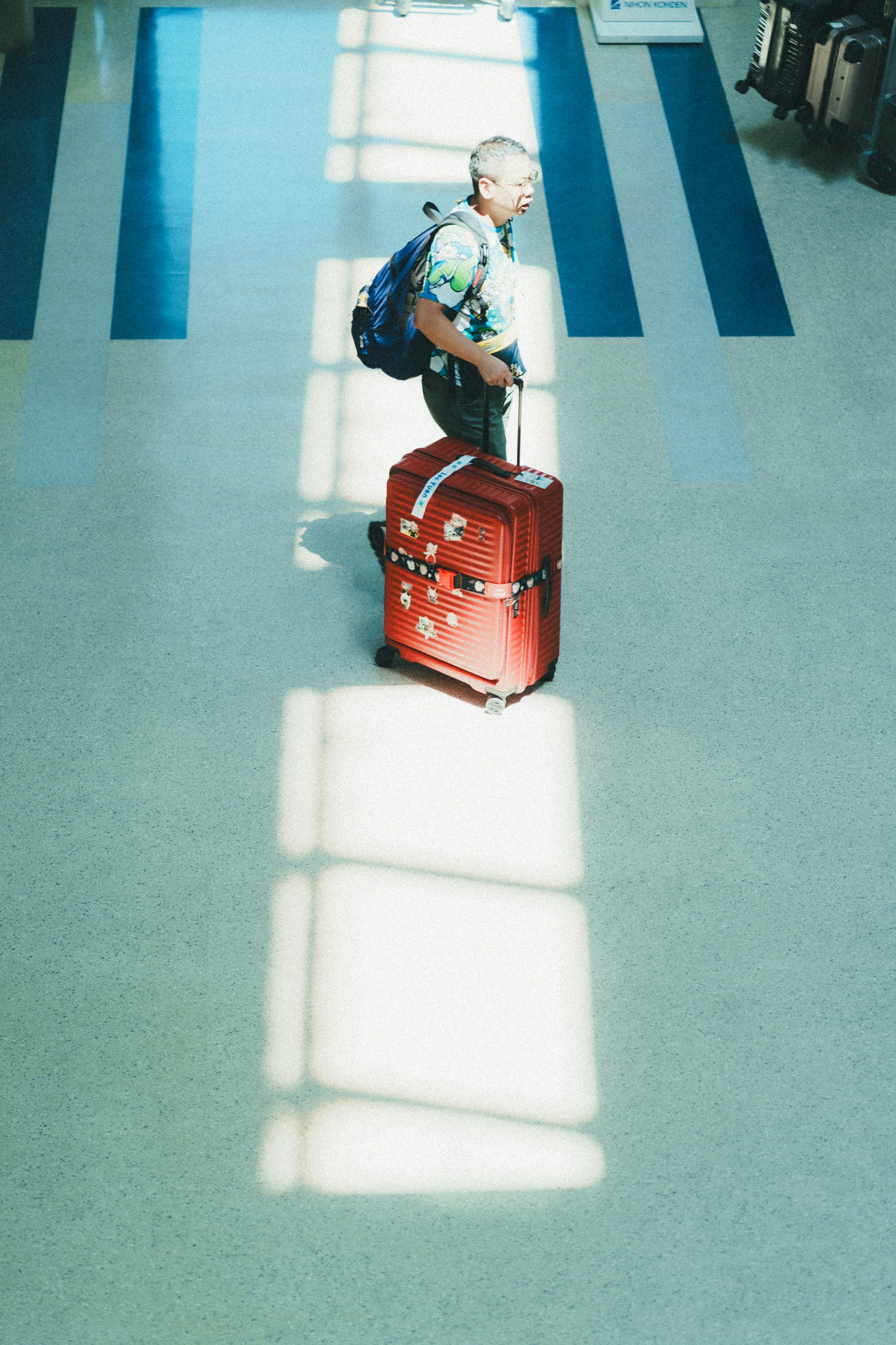 Homme tirant une valise rouge dans un terminal d'aéroport