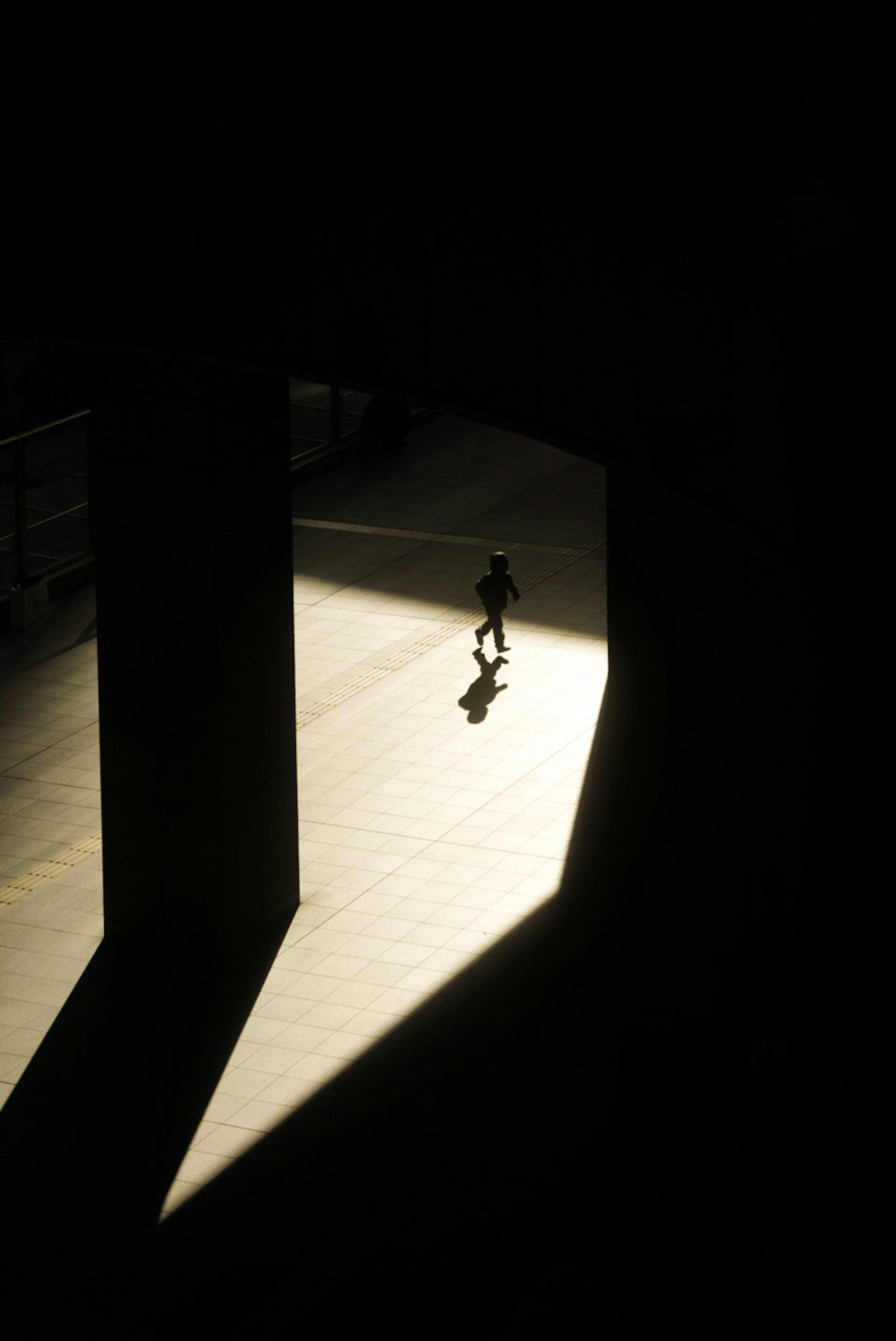 A person walking in a beam of light within a dark space