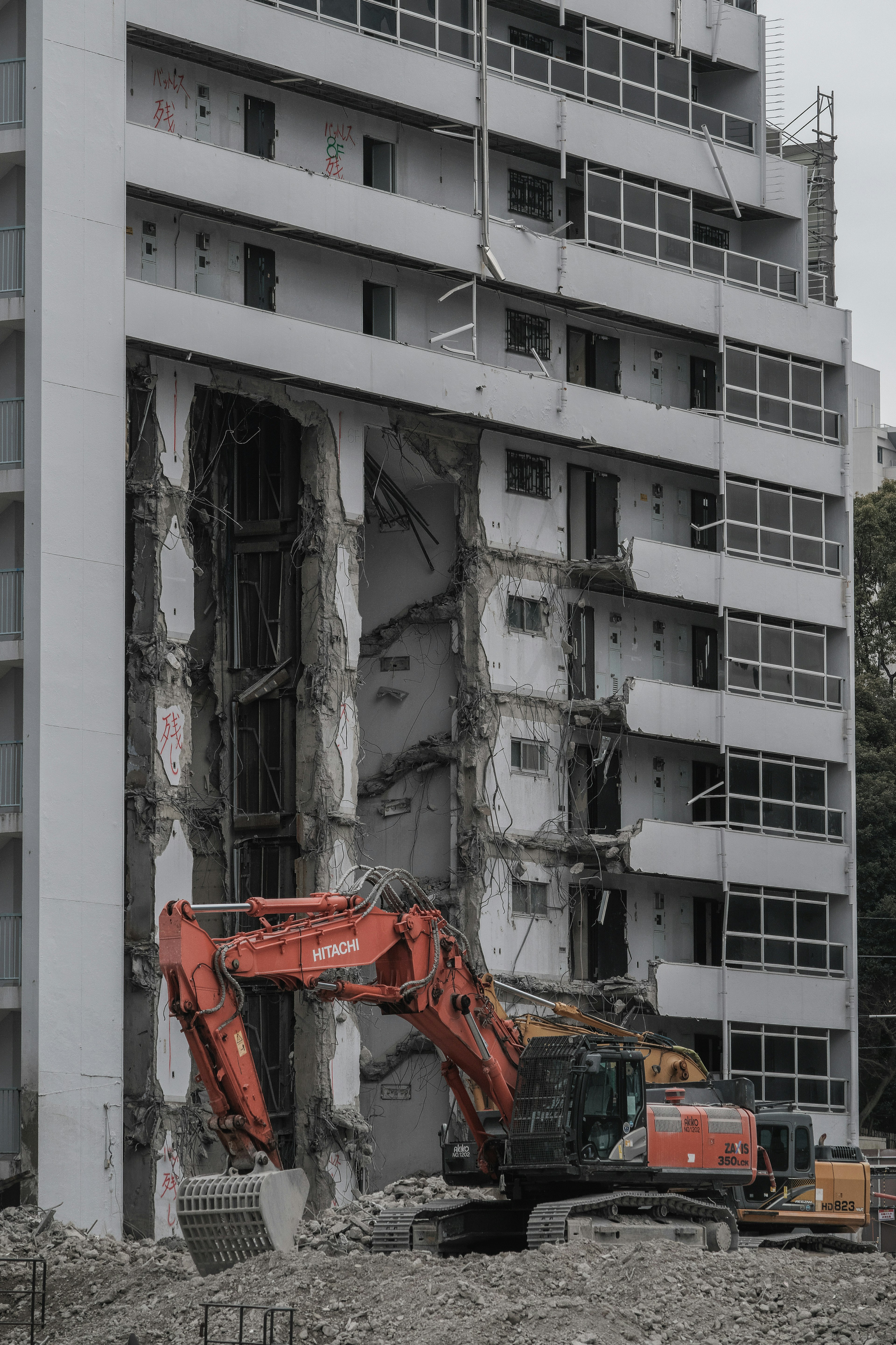 Demolition work in progress with heavy machinery and collapsed concrete wall