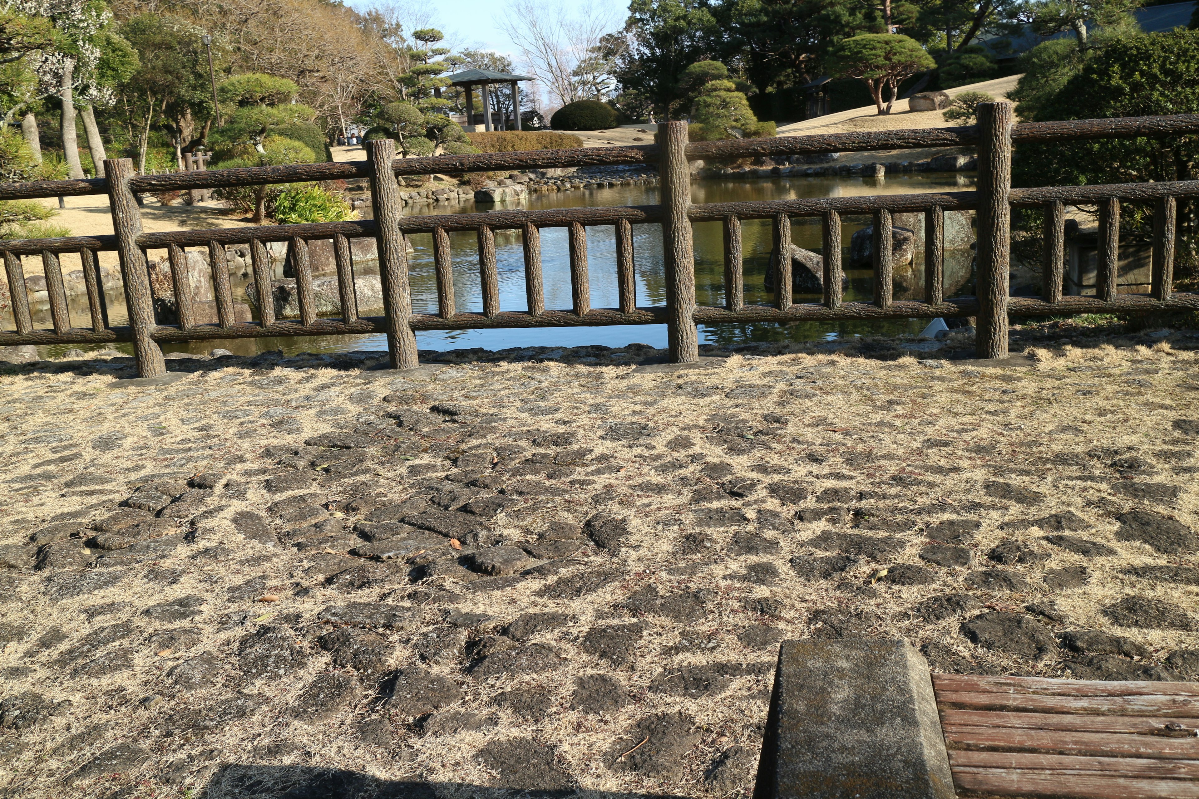 Vista escénica de una cerca de madera cerca de un río con un camino de arena