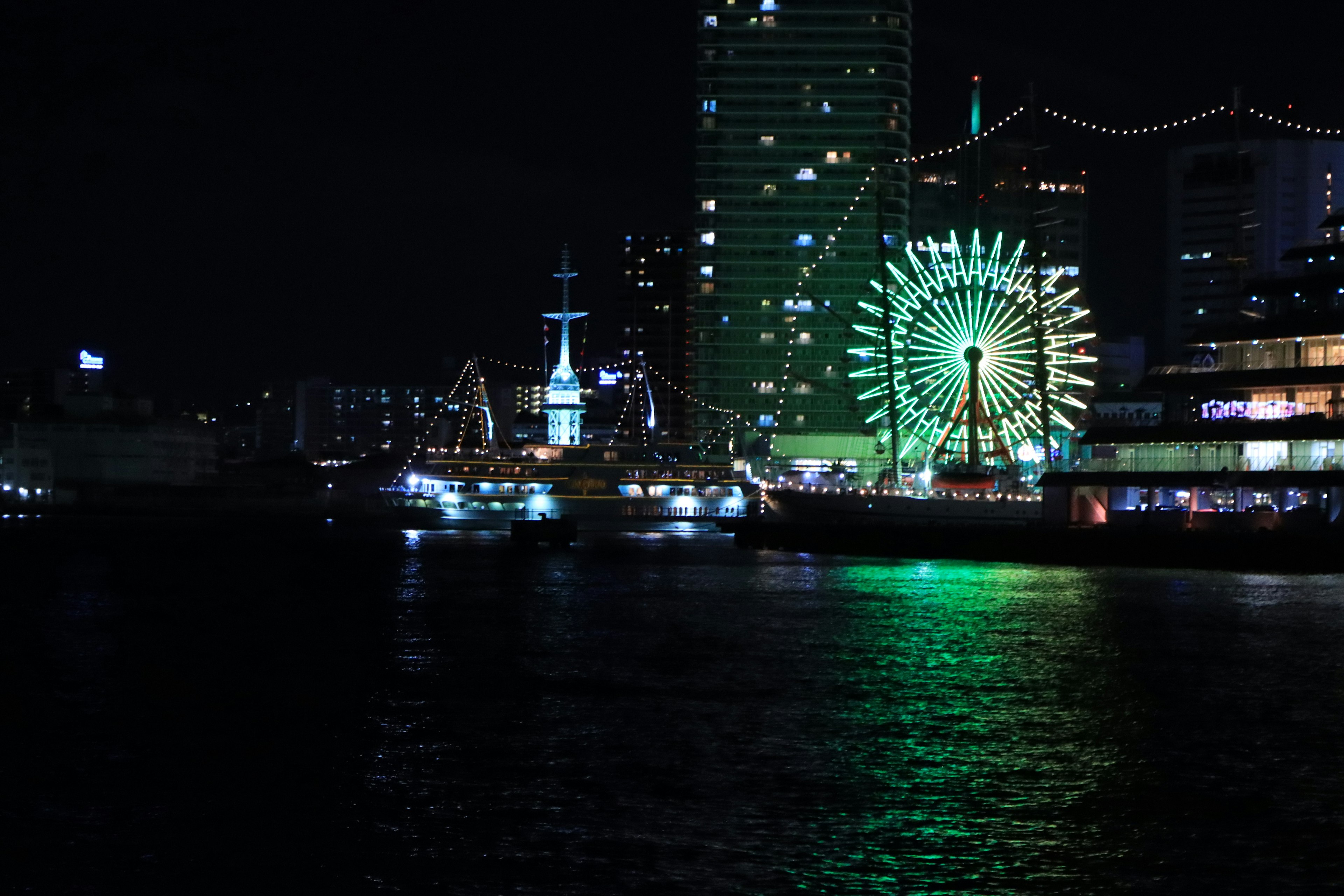 夜晚港口的景观，有着明亮的摩天轮和船只