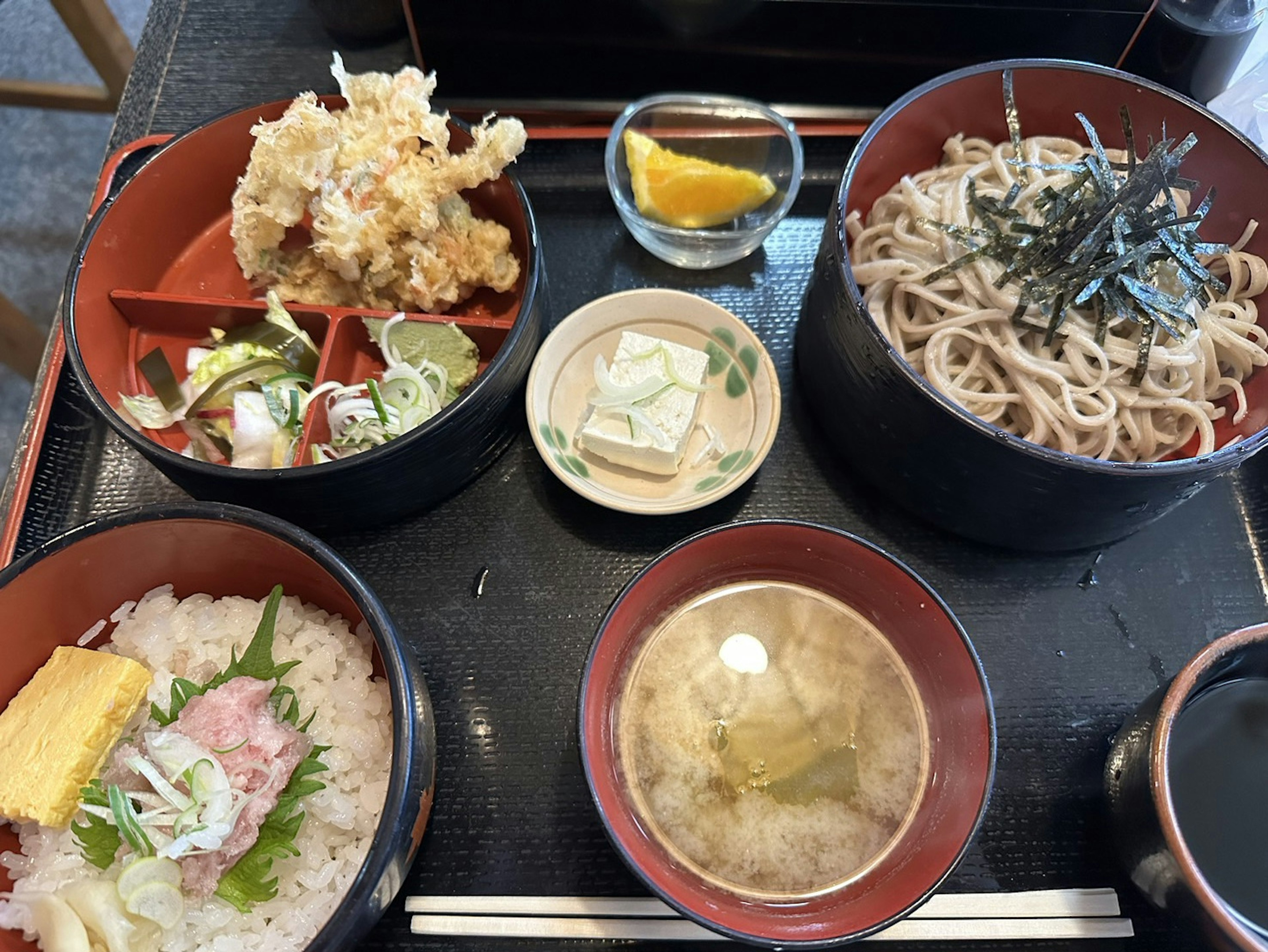 Japanese meal set featuring tempura soba miso soup and chirashi sushi