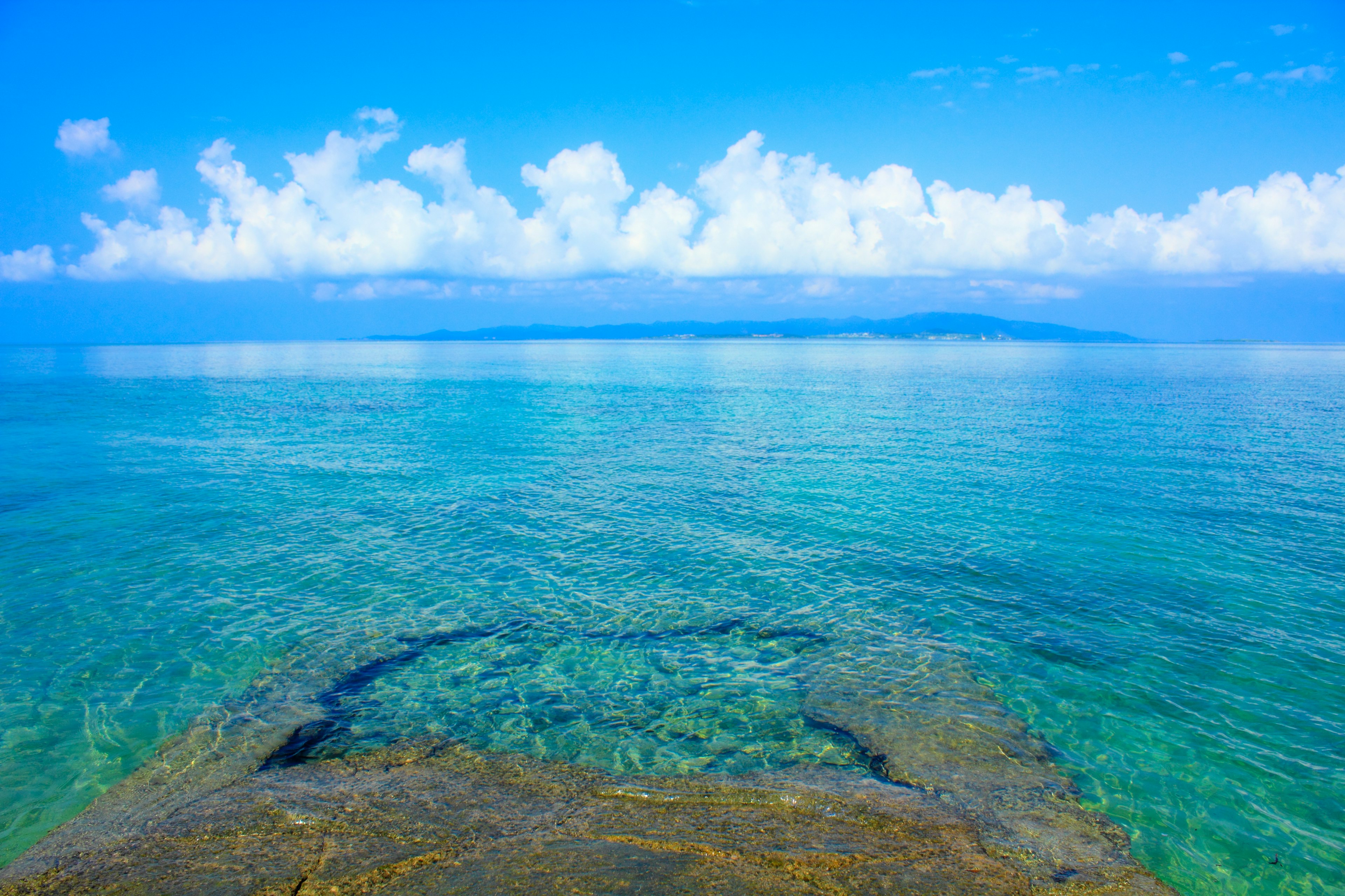 Pemandangan laut biru dan langit dengan air jernih dan awan putih