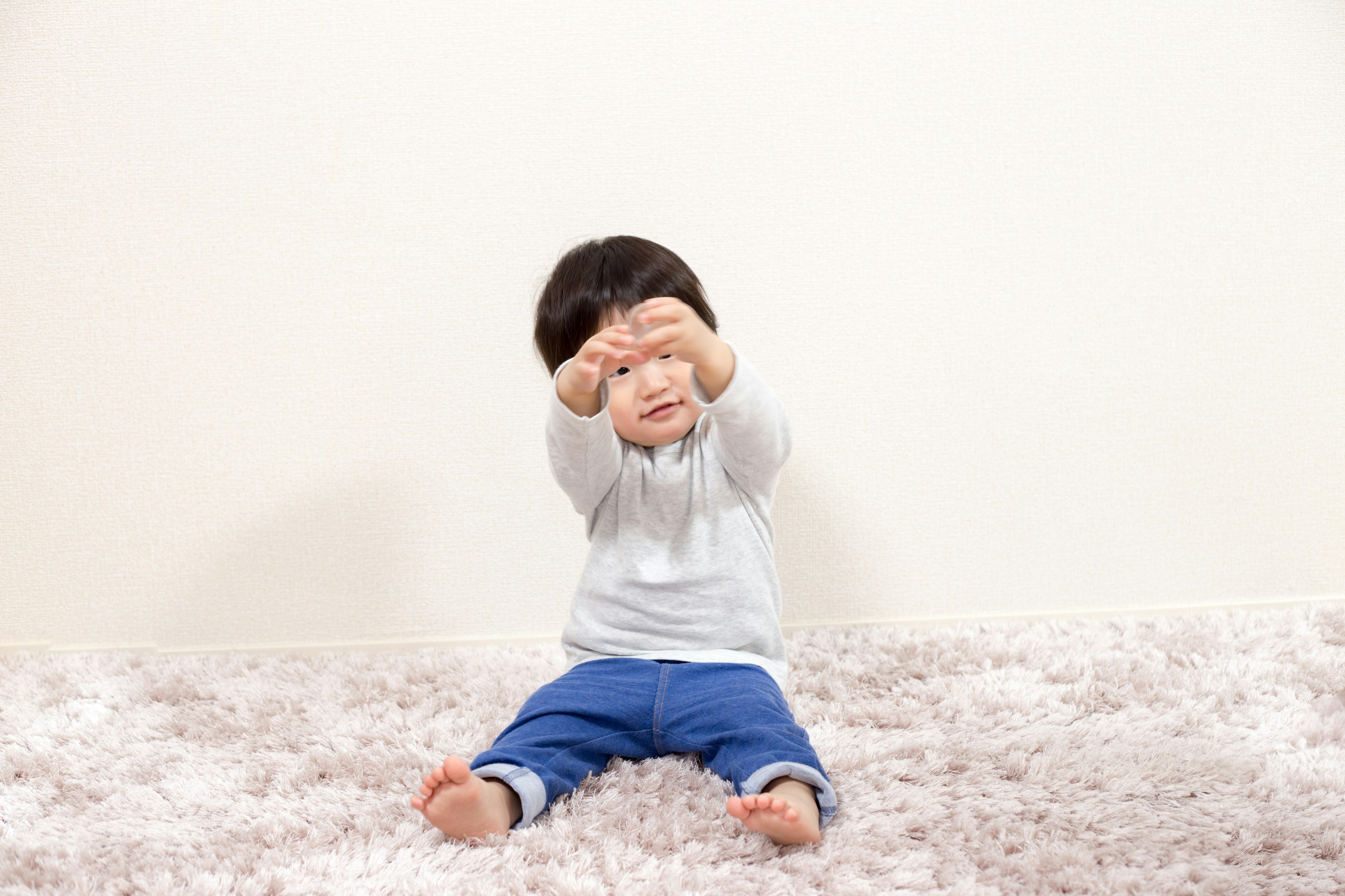 Seorang anak kecil duduk dan mengulurkan tangan