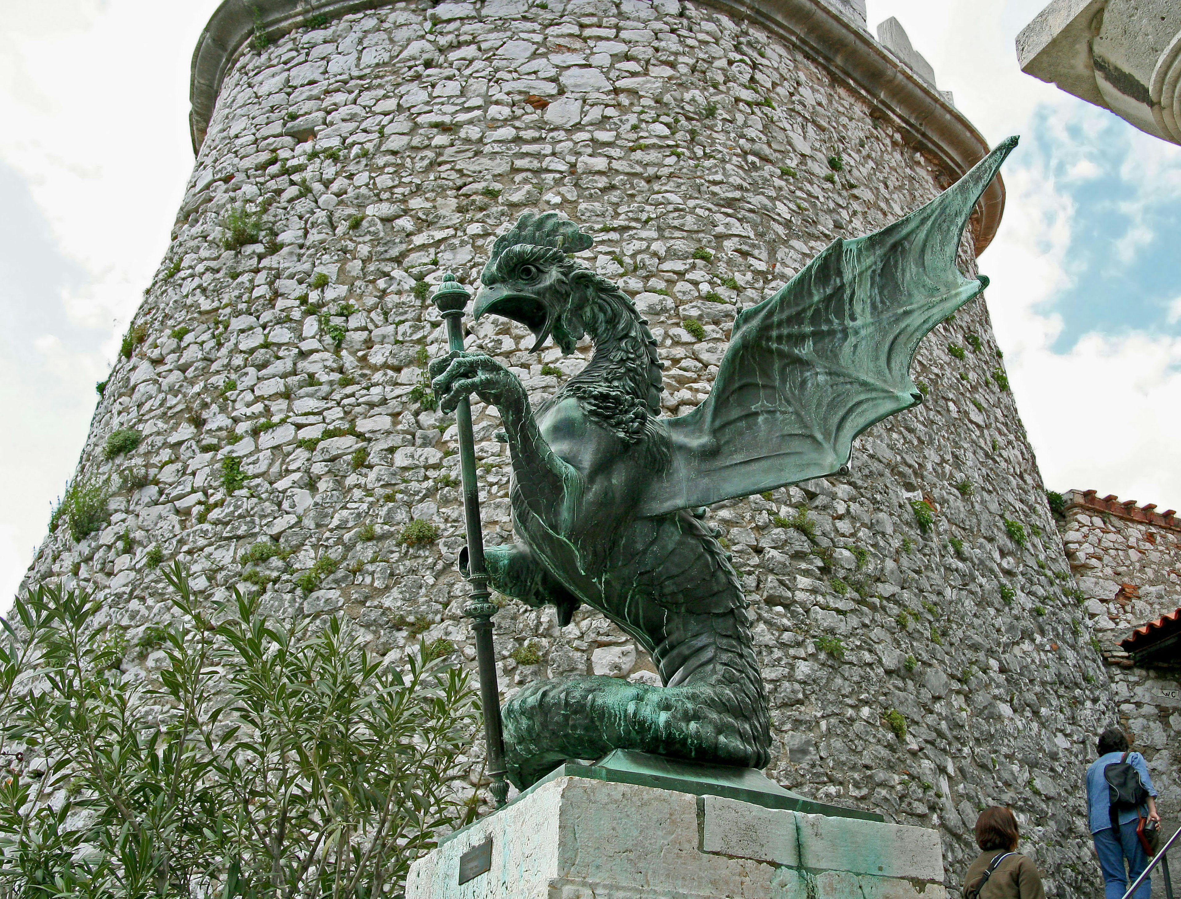 Statua di drago in bronzo davanti a una torre di pietra