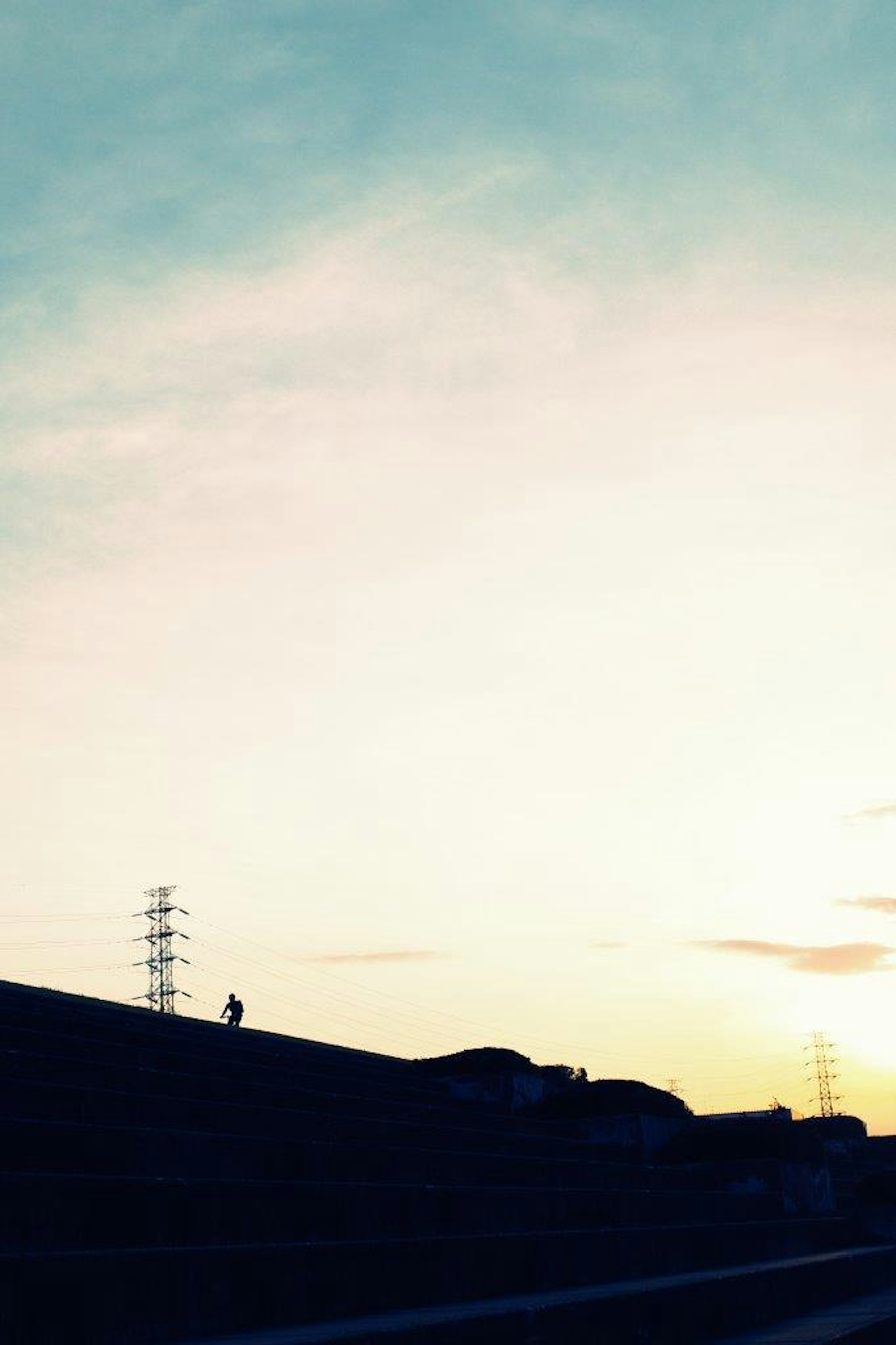 Silueta de una colina bajo un cielo azul con atardecer y líneas eléctricas