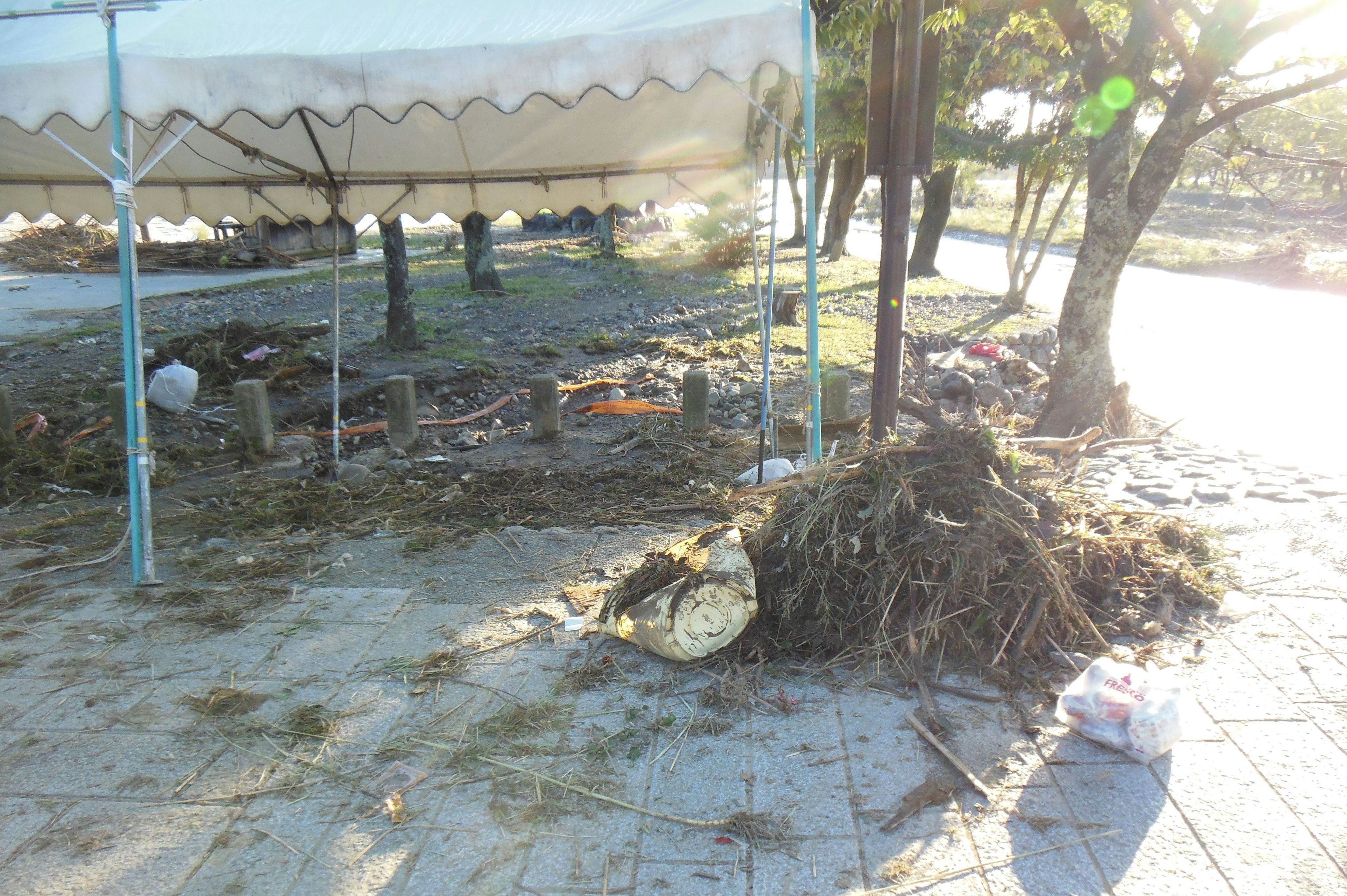 A pile of debris and grass near a tent with a sunny background