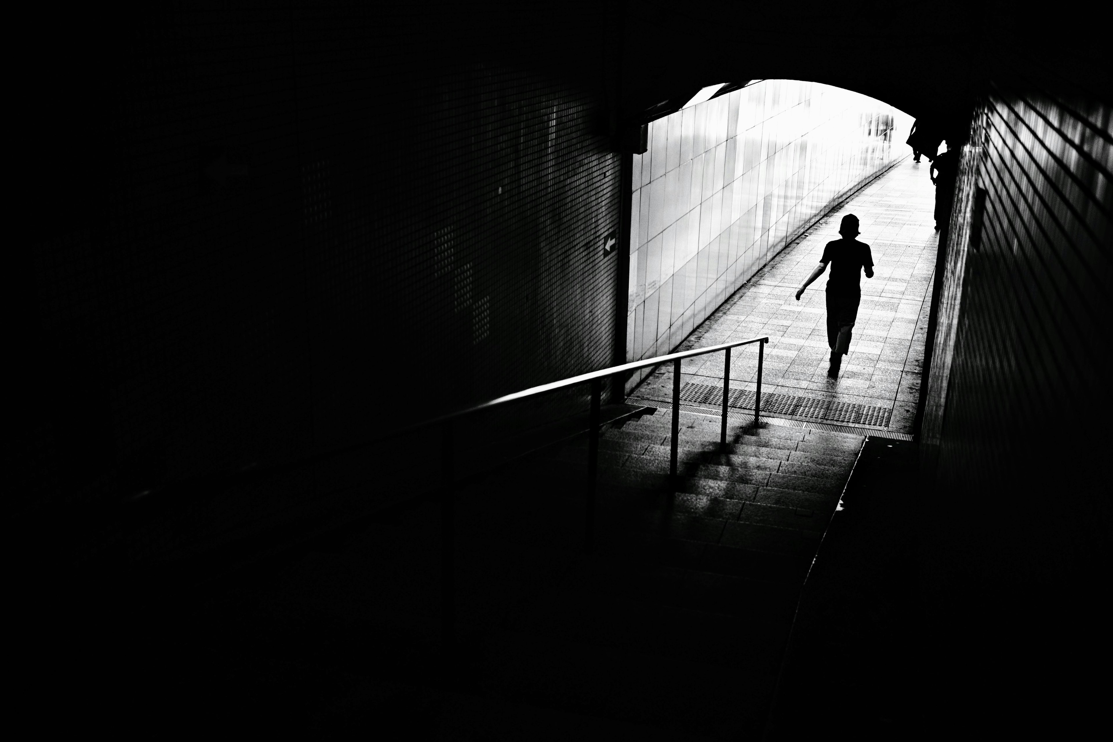 Silhouette d'une personne se tenant à la sortie d'un tunnel sombre