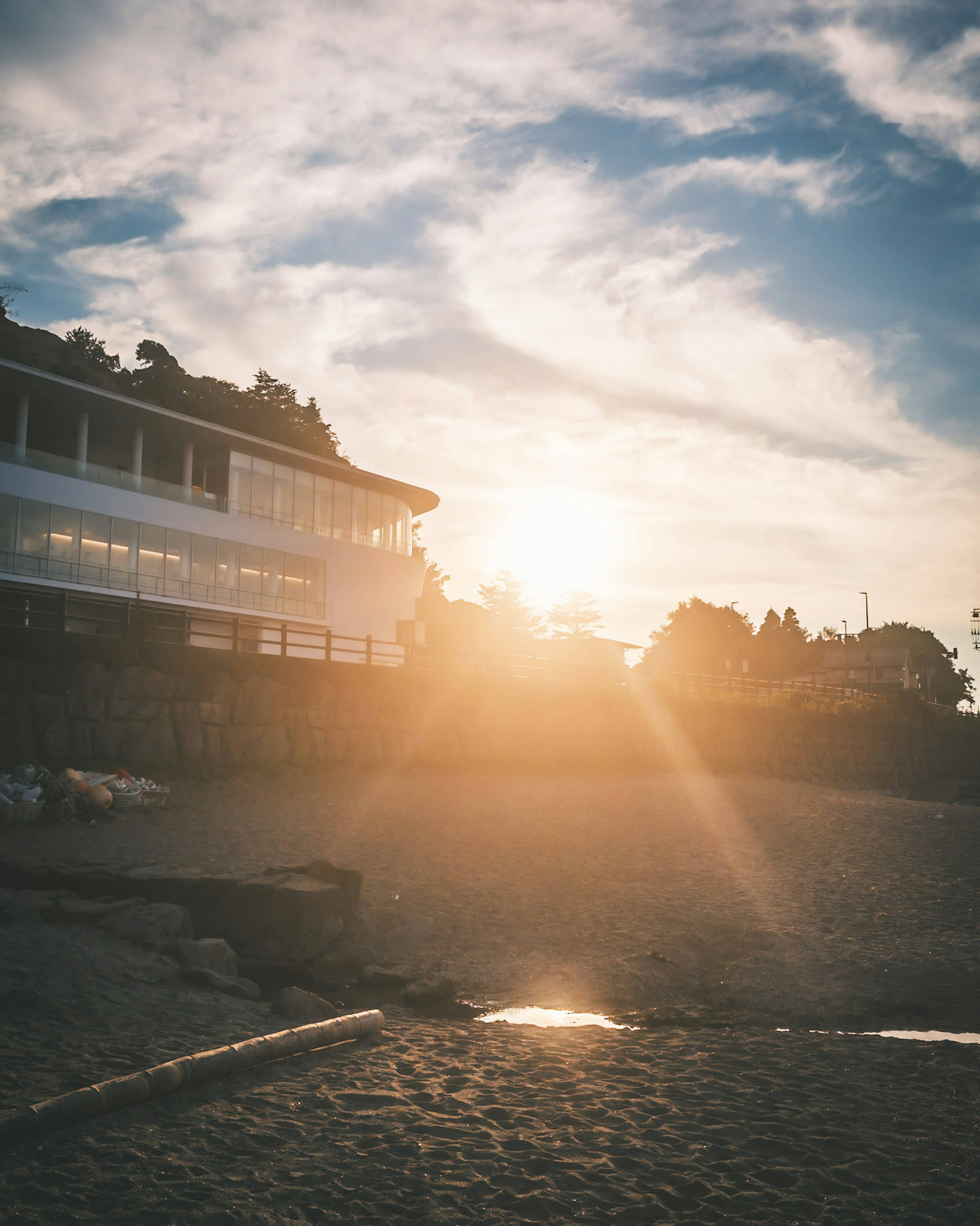 Beach scene with a shining sunset and a building