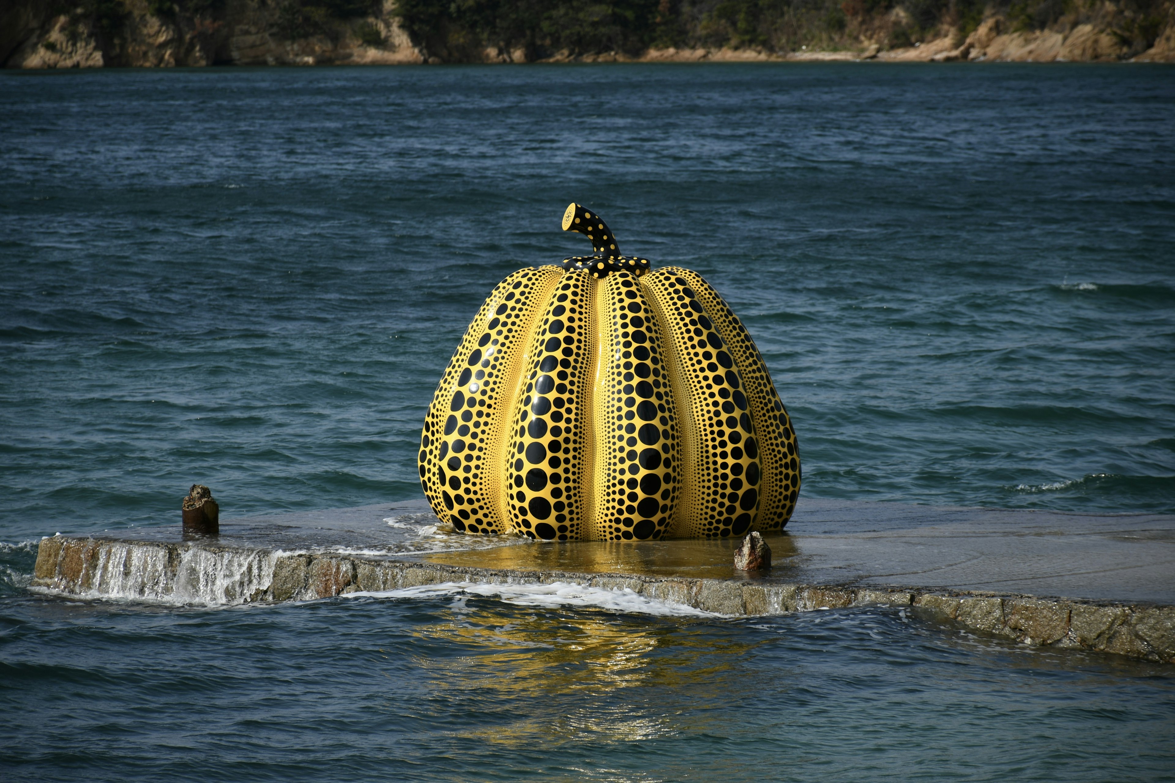 Escultura de calabaza amarilla flotando en el agua