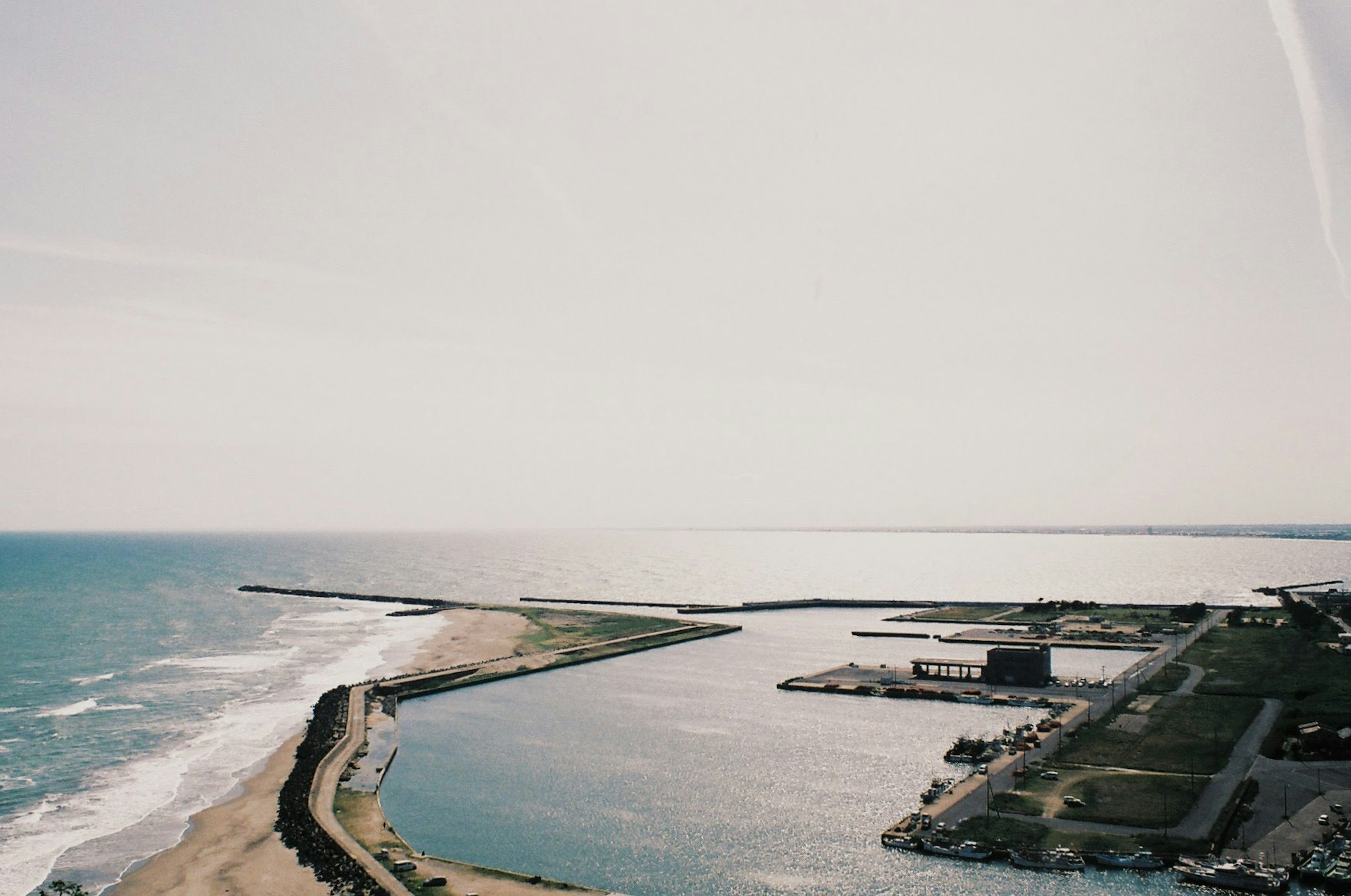 Vista aérea de una playa y el océano con un puerto y estructuras de rompeolas