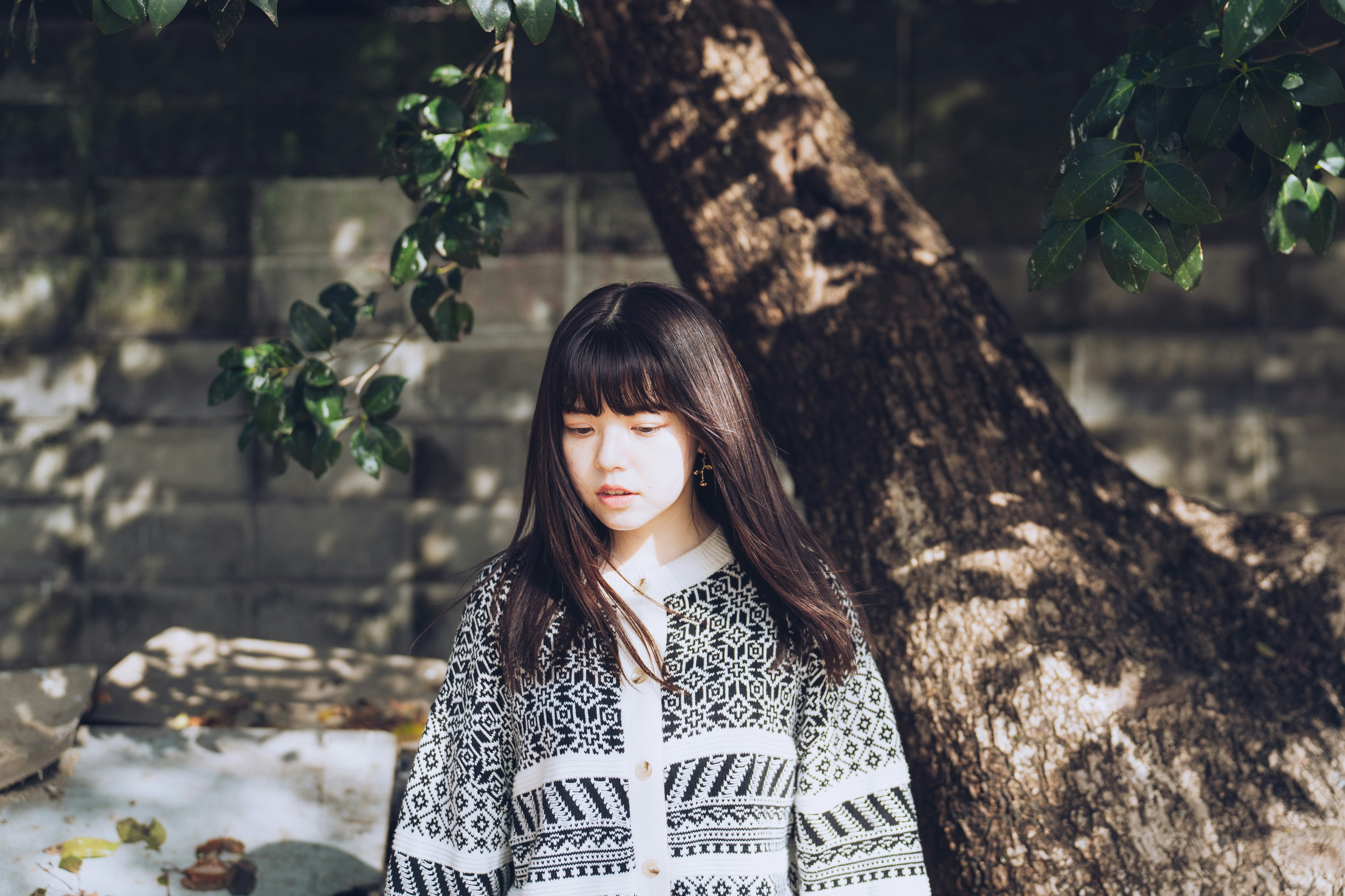 A woman standing under a tree wearing a monochrome sweater