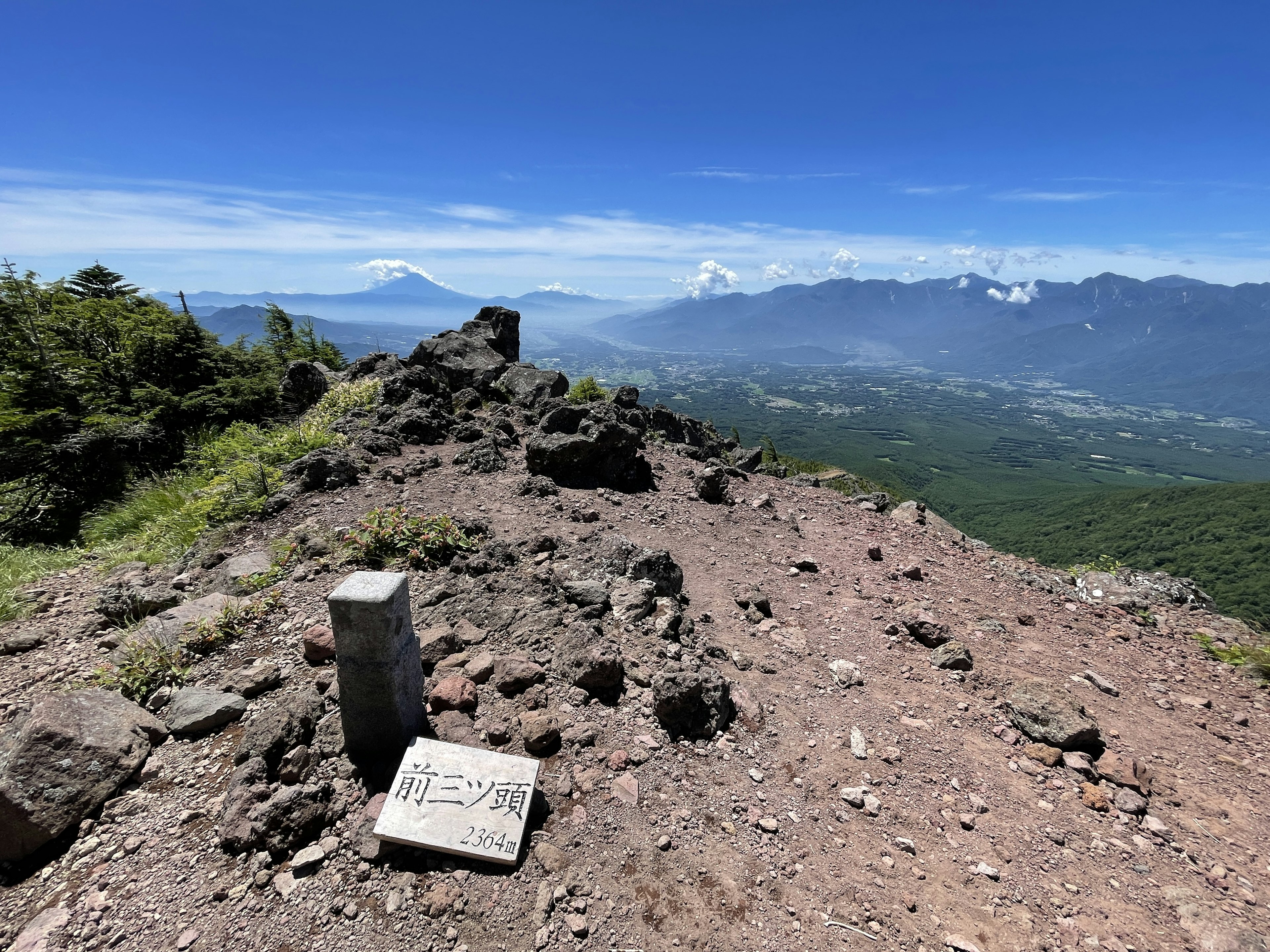 Vista desde la cima de una montaña con un cartel y terreno rocoso