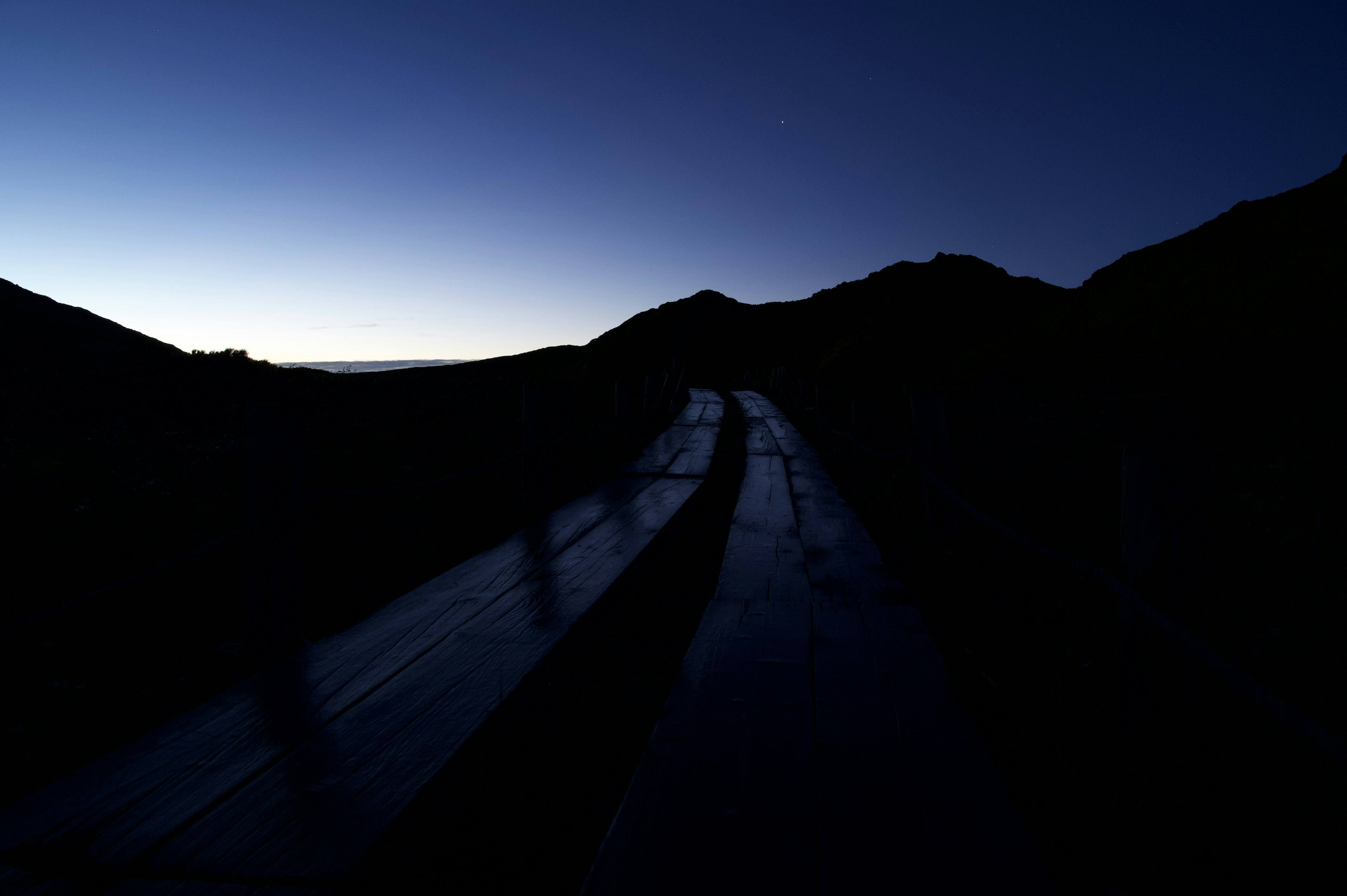 Camino de montaña al amanecer con siluetas y luz suave