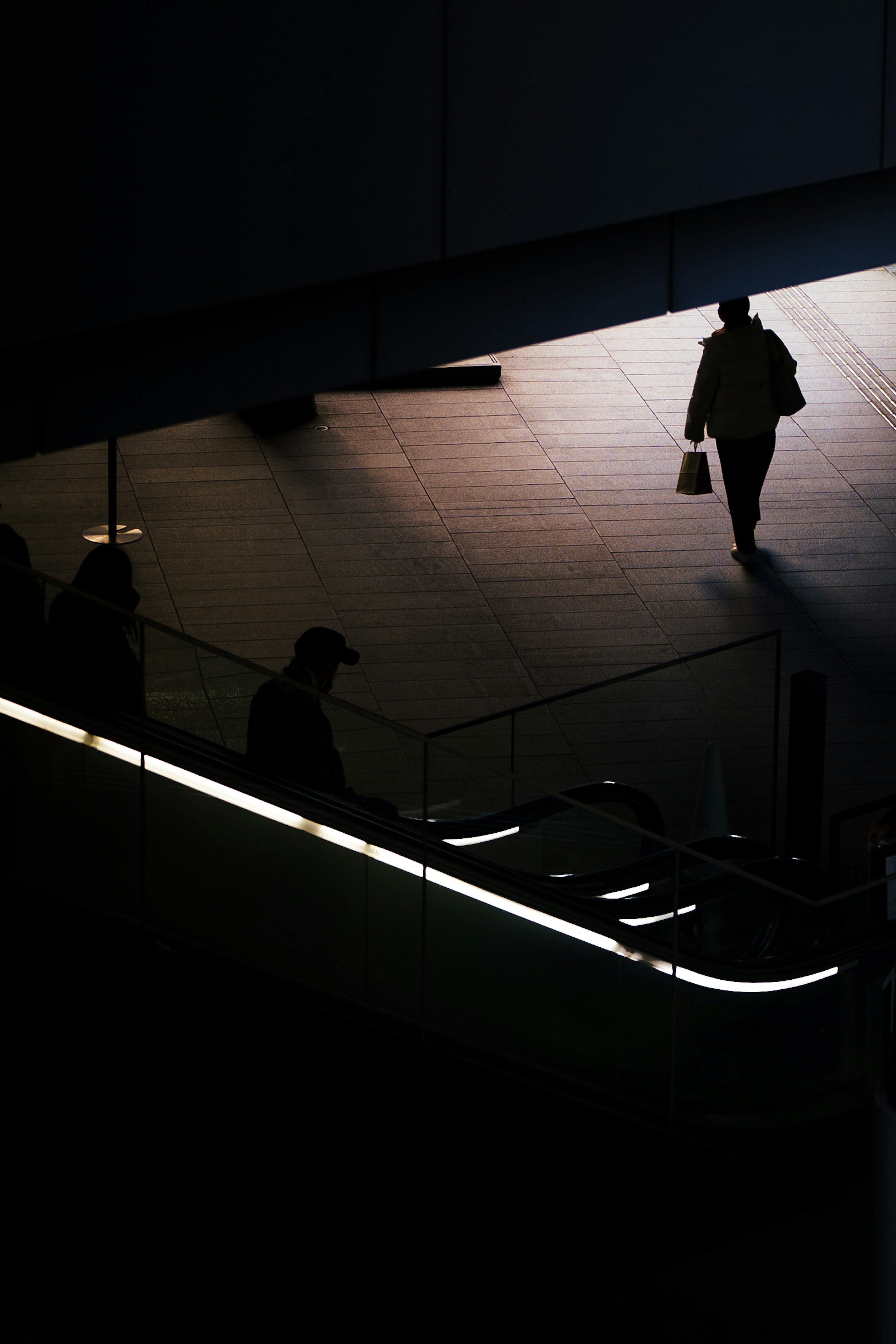 Silhouette di una persona che cammina con riflessi di luce su uno sfondo scuro