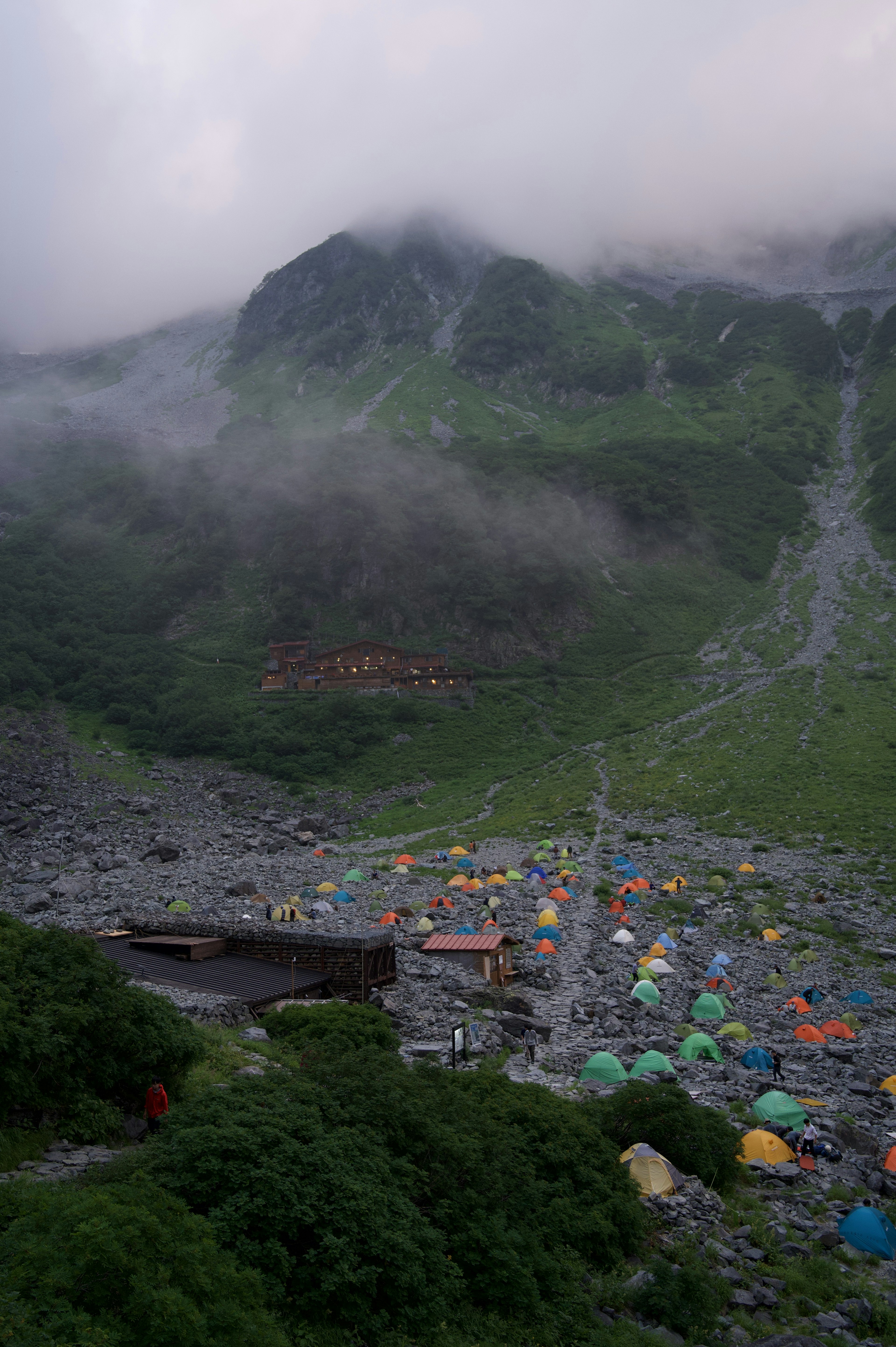 A landscape featuring colorful tents scattered in a misty mountainous area