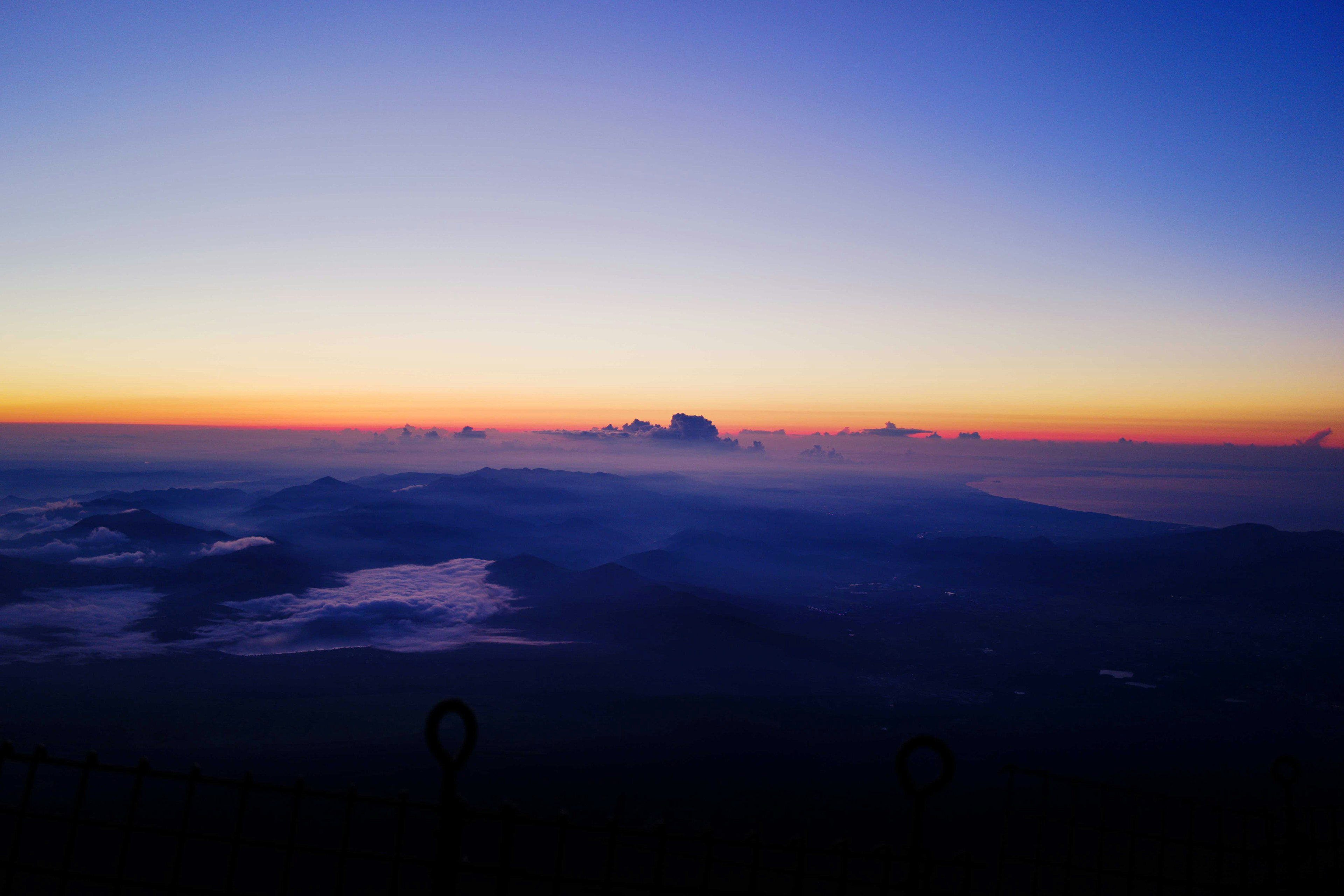 Stupenda vista dell'alba con un cielo sfumato che va dal blu all'arancione con nuvole e montagne