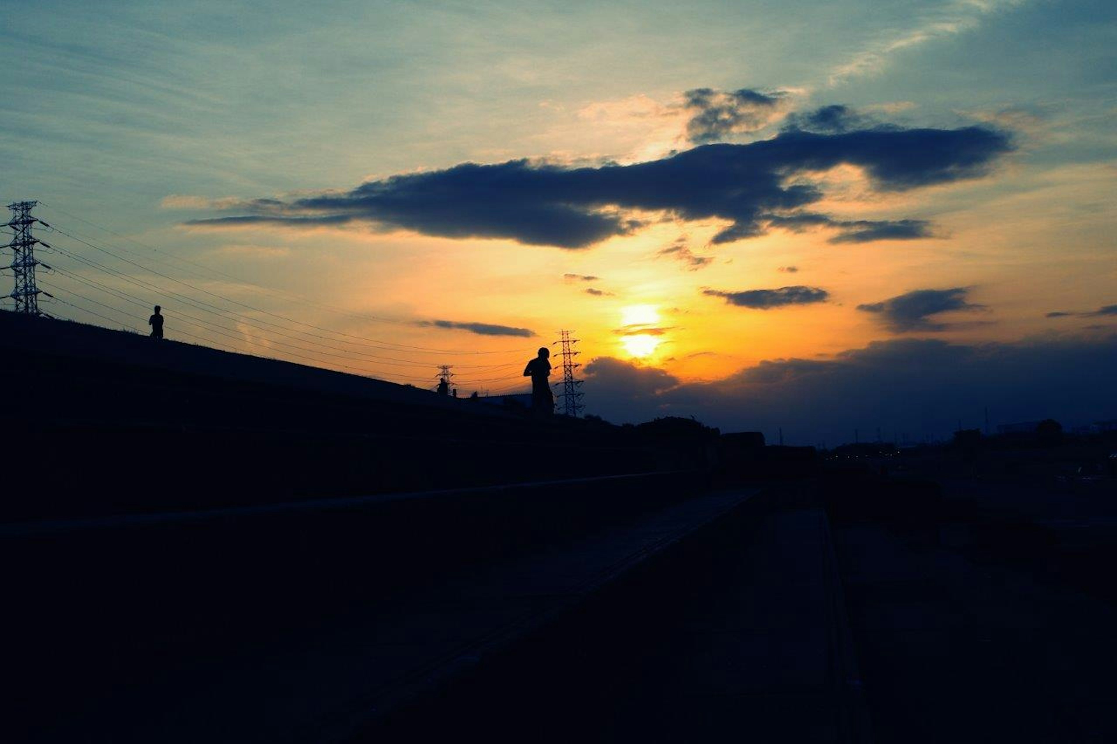 夕焼けの空とシルエットの風景に電柱が立っている