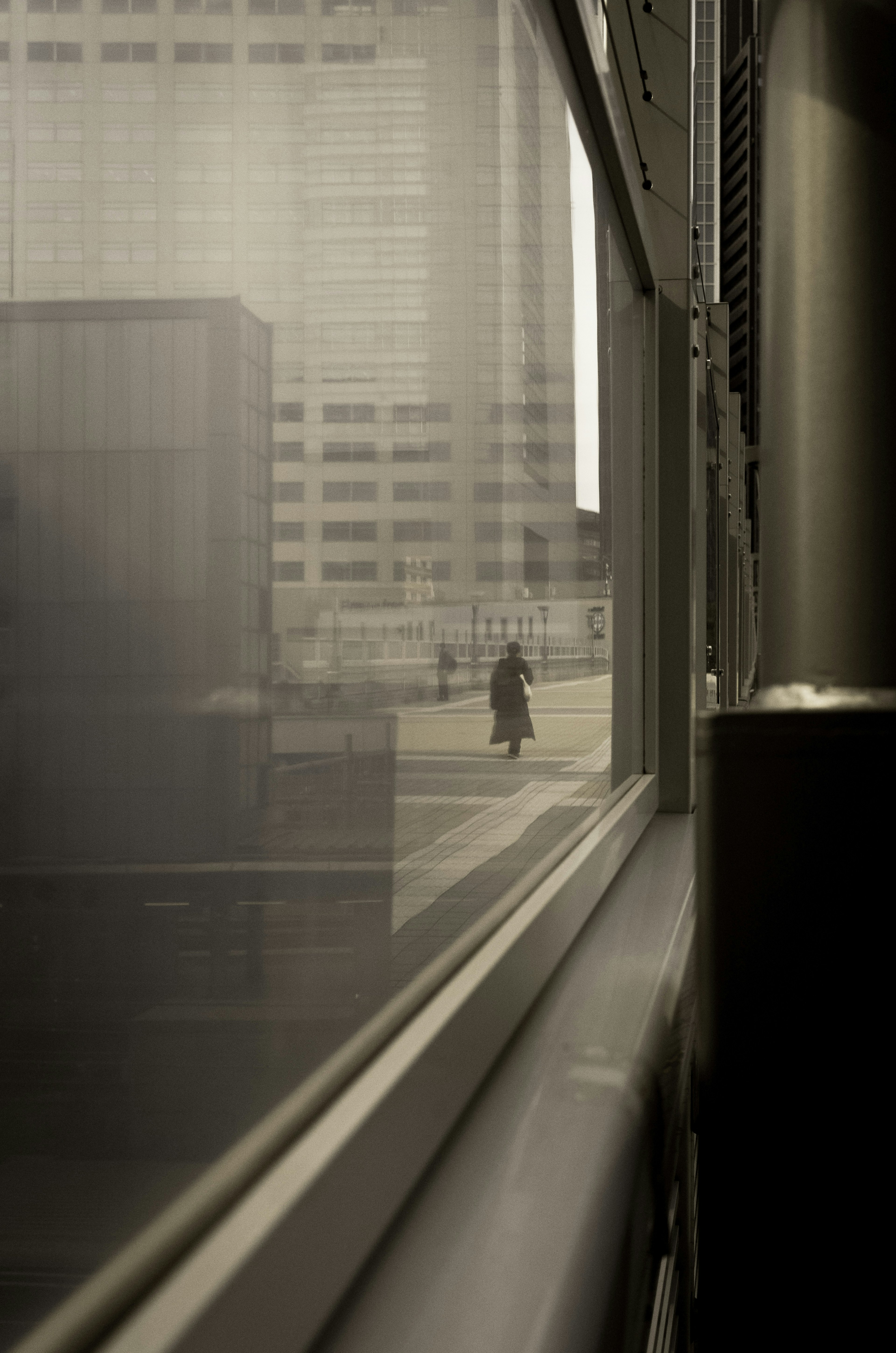 Cityscape viewed through a foggy window featuring a solitary pedestrian