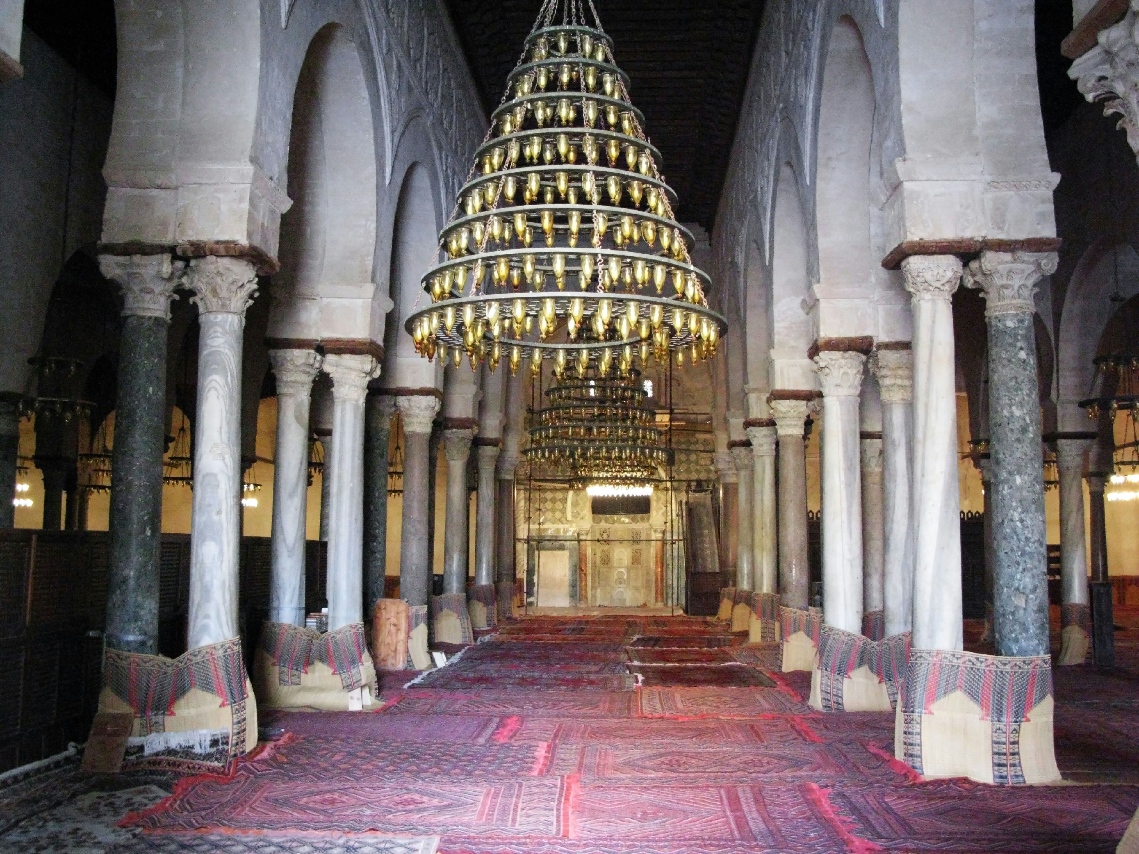 Interior of a beautiful mosque featuring arched columns and a decorative chandelier with a red carpeted floor