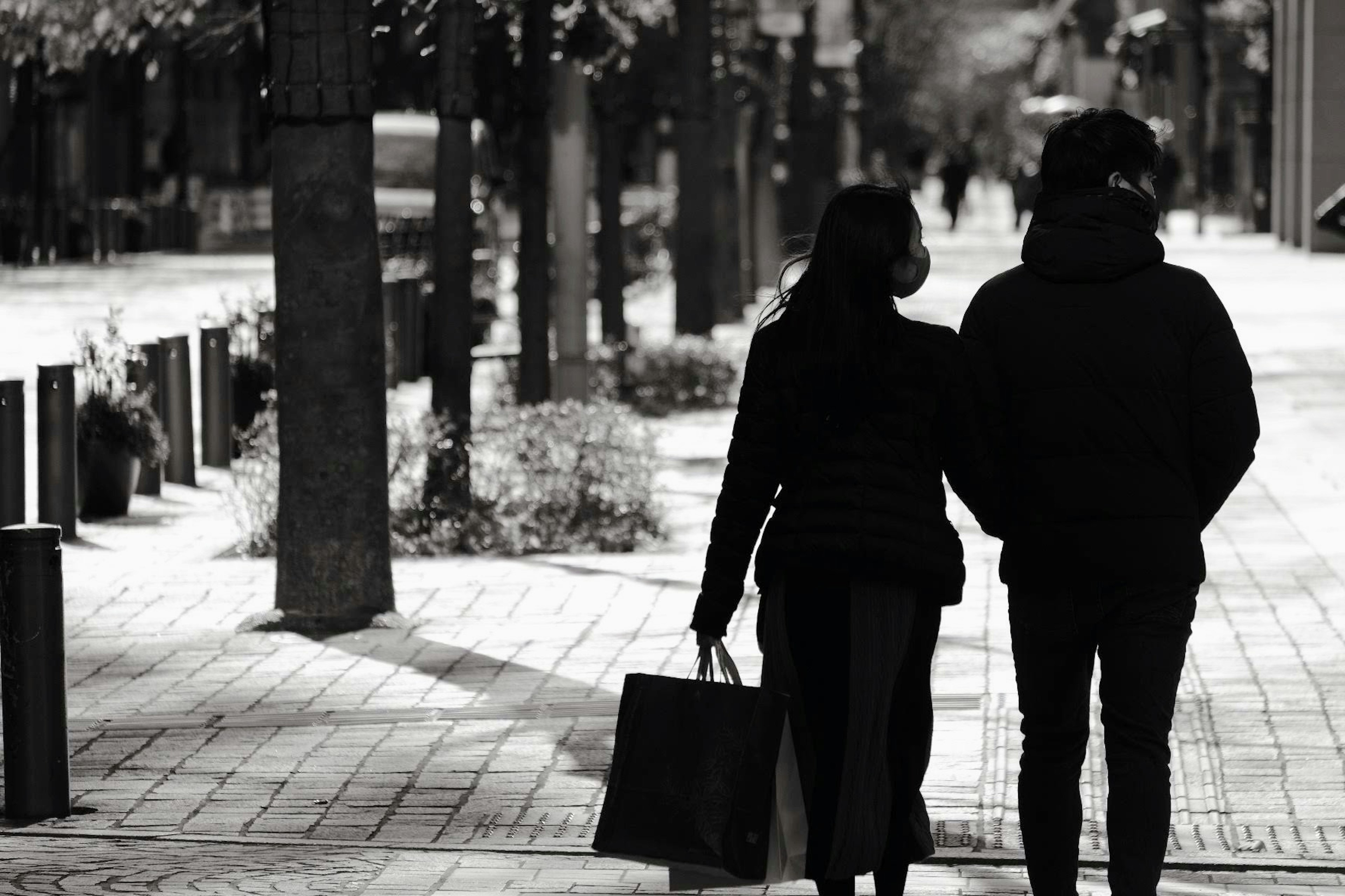 Pareja caminando de la mano por una calle de la ciudad con abrigos negros