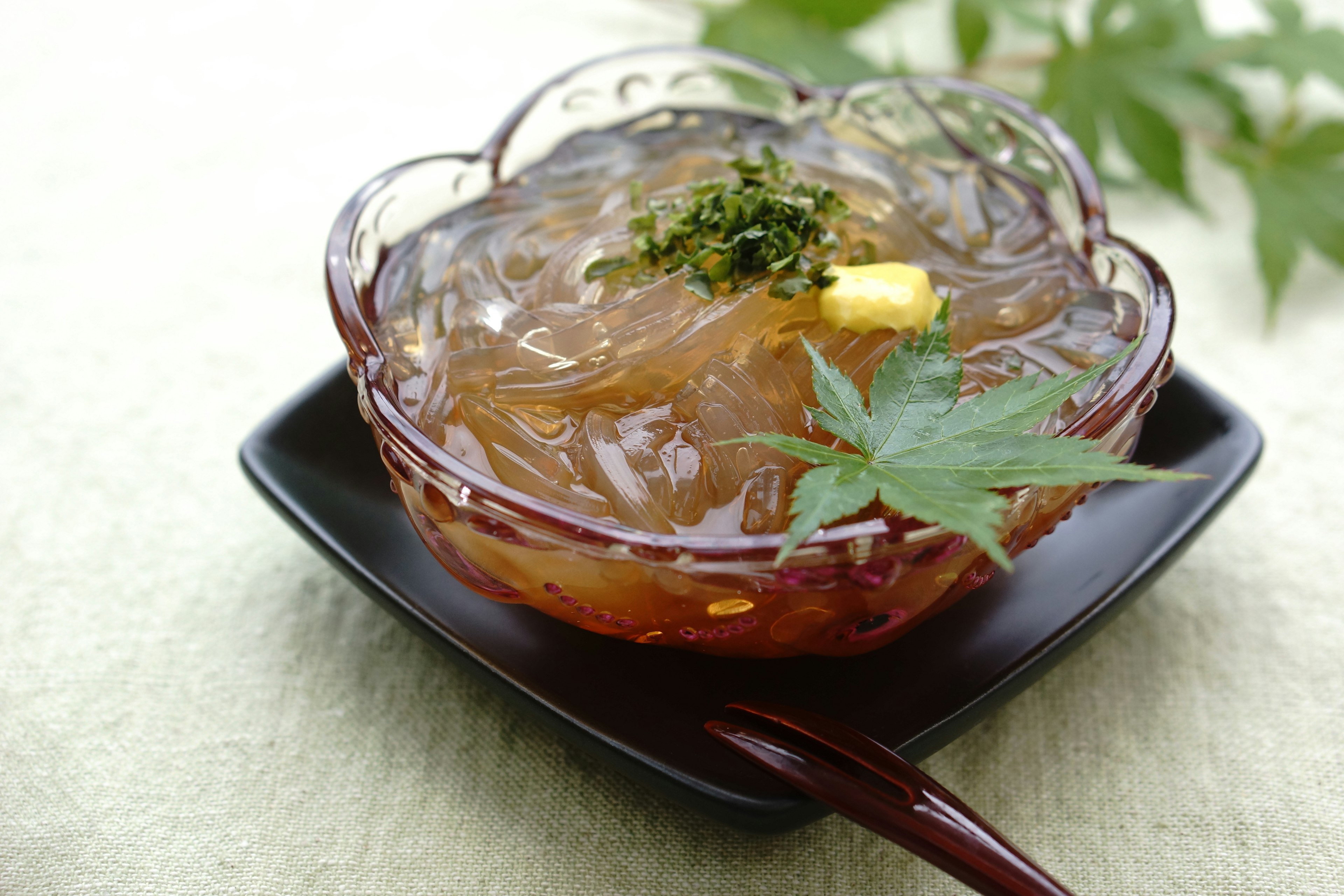 A beautiful dessert bowl filled with translucent agar jelly garnished with green leaves and a slice of lemon