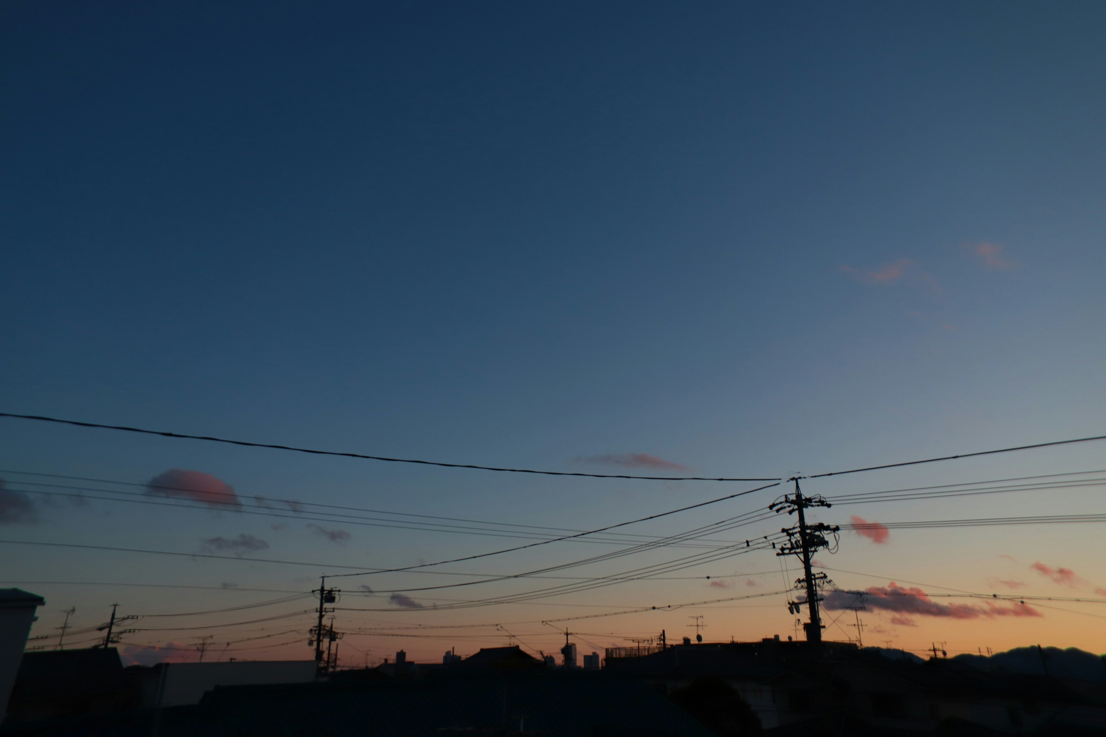 Cielo al atardecer con líneas eléctricas y techos