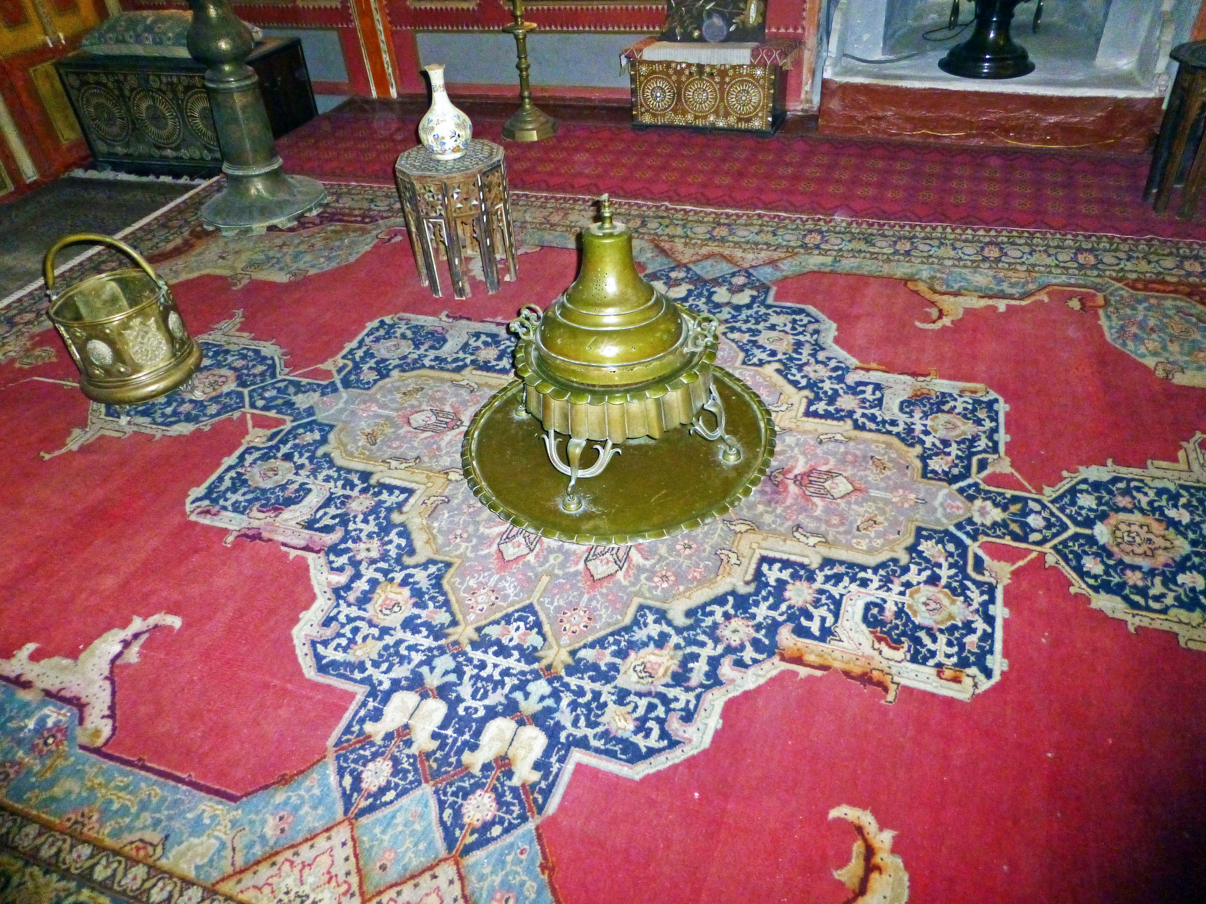 Interior de una habitación con una alfombra roja y objetos decorativos dorados