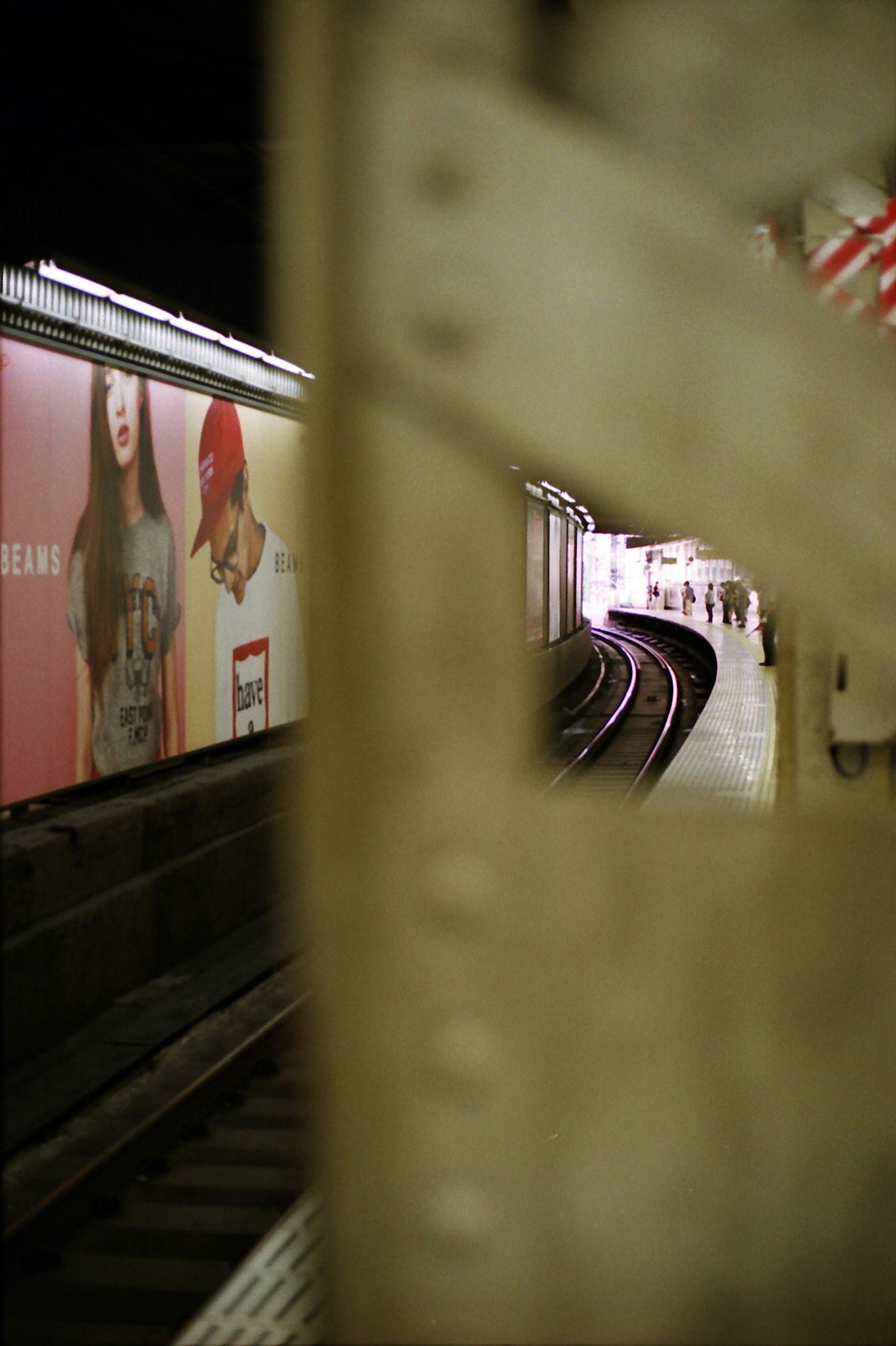 Imagen de una estación de metro con vías de tren y un anuncio en la pared