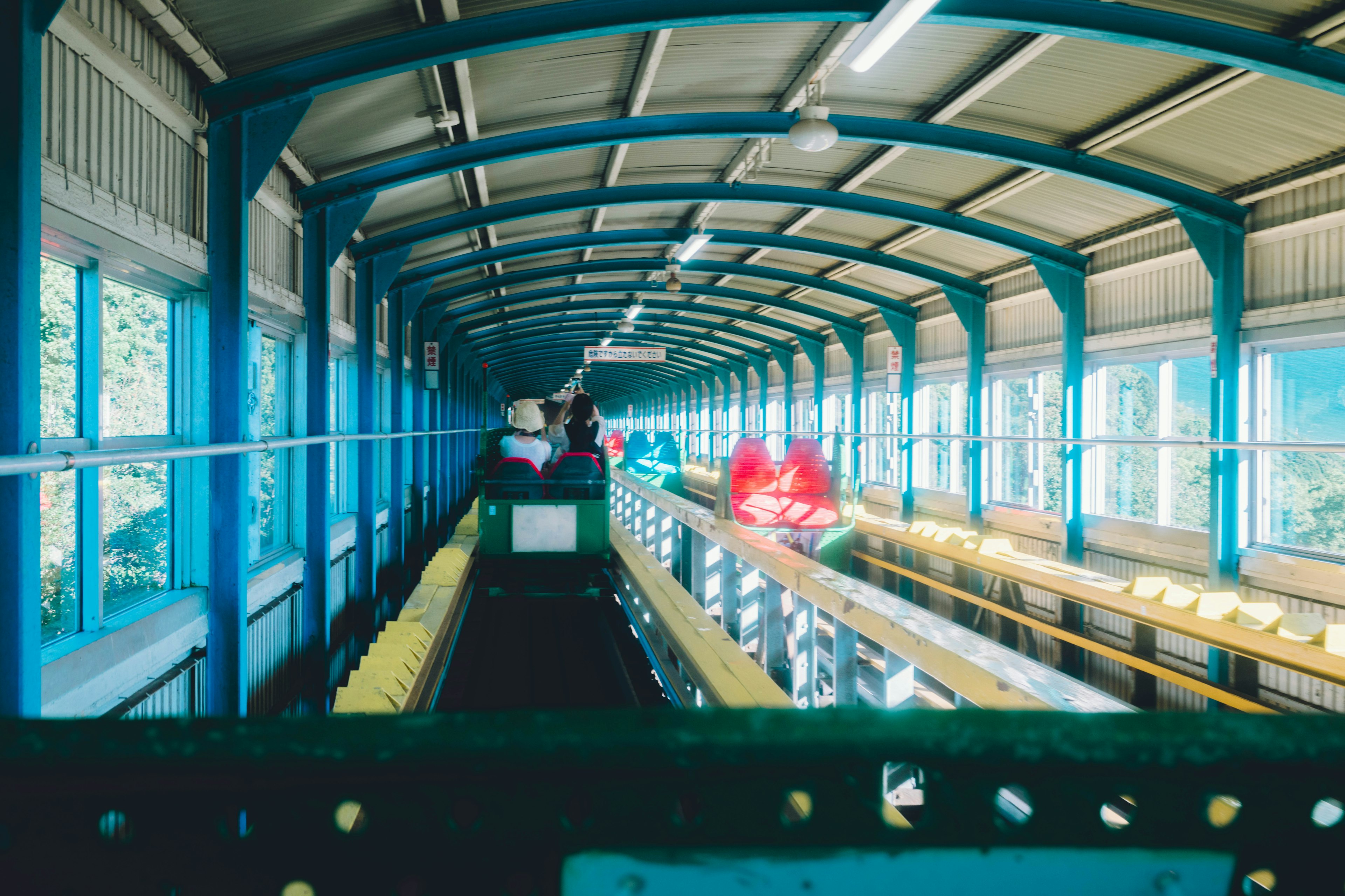 Long corridor under a blue roof with people lined up