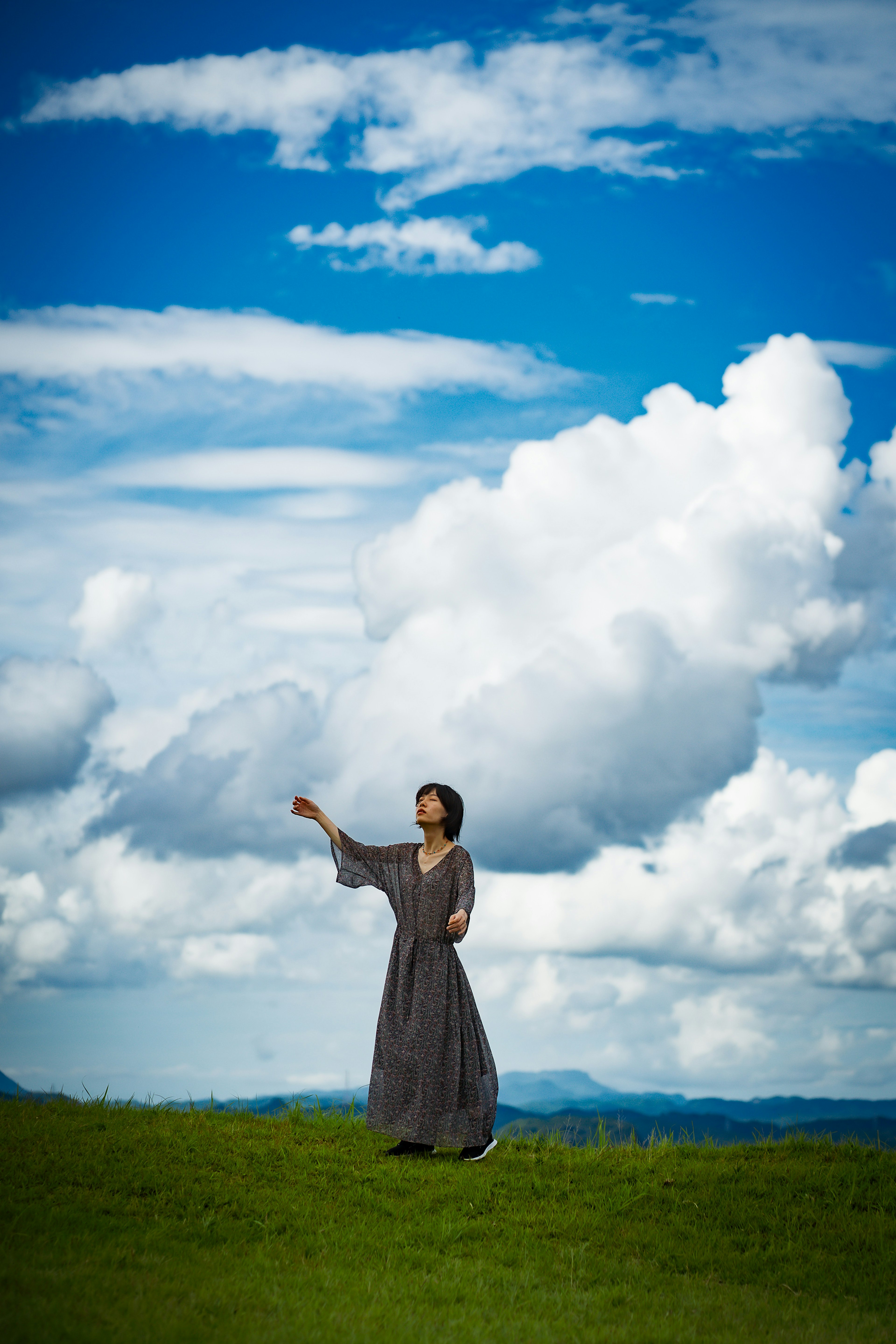 Eine Frau, die auf einem grasbewachsenen Feld steht und unter einem blauen Himmel winkt