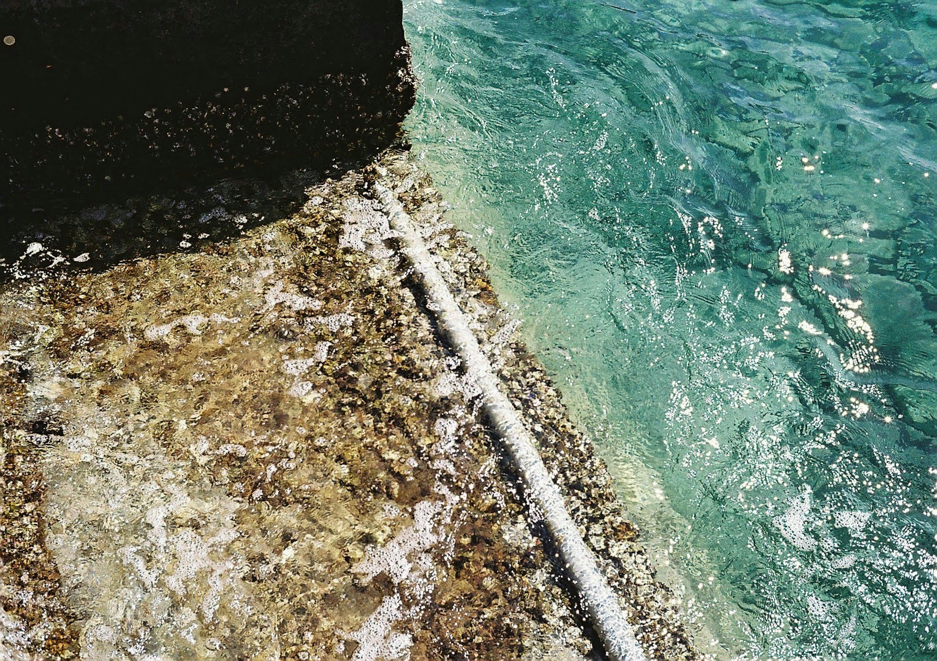 海の水と岩の境界線の近くの砂利の岸