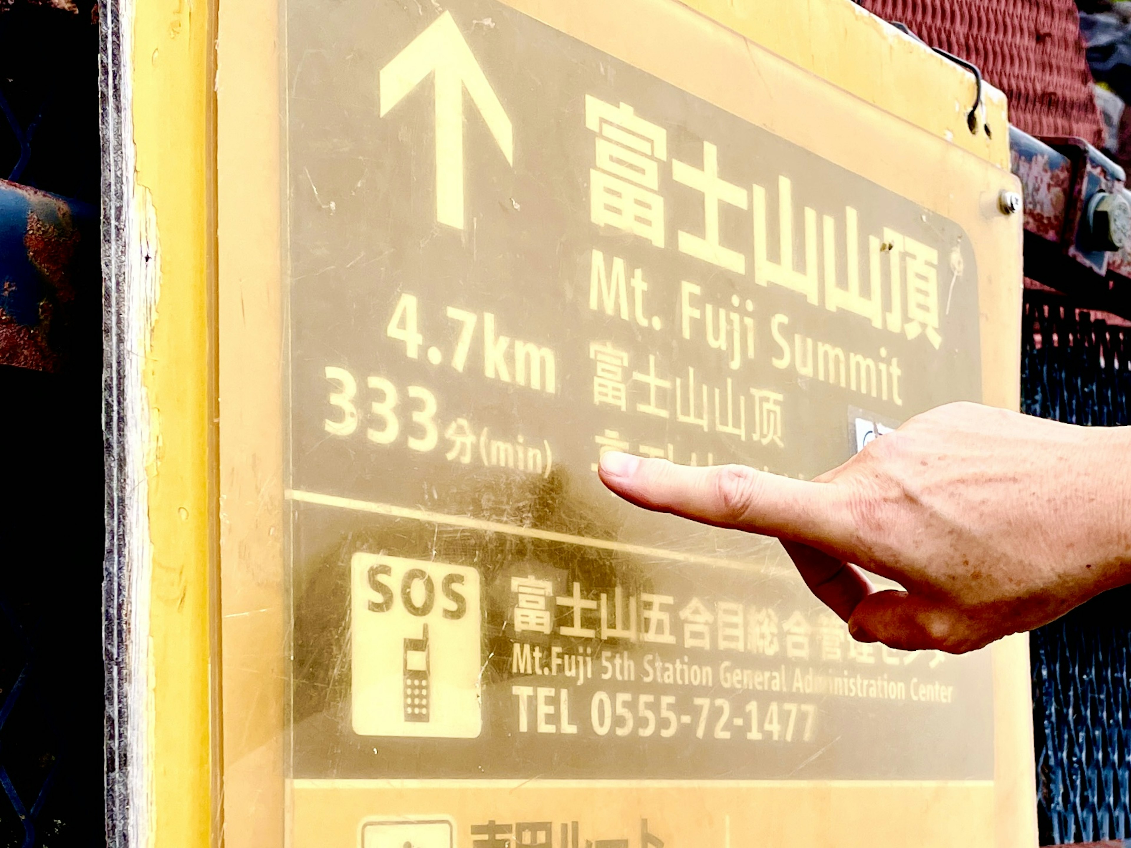 Cartel amarillo que indica la distancia hasta la cumbre del Monte Fuji con una flecha direccional