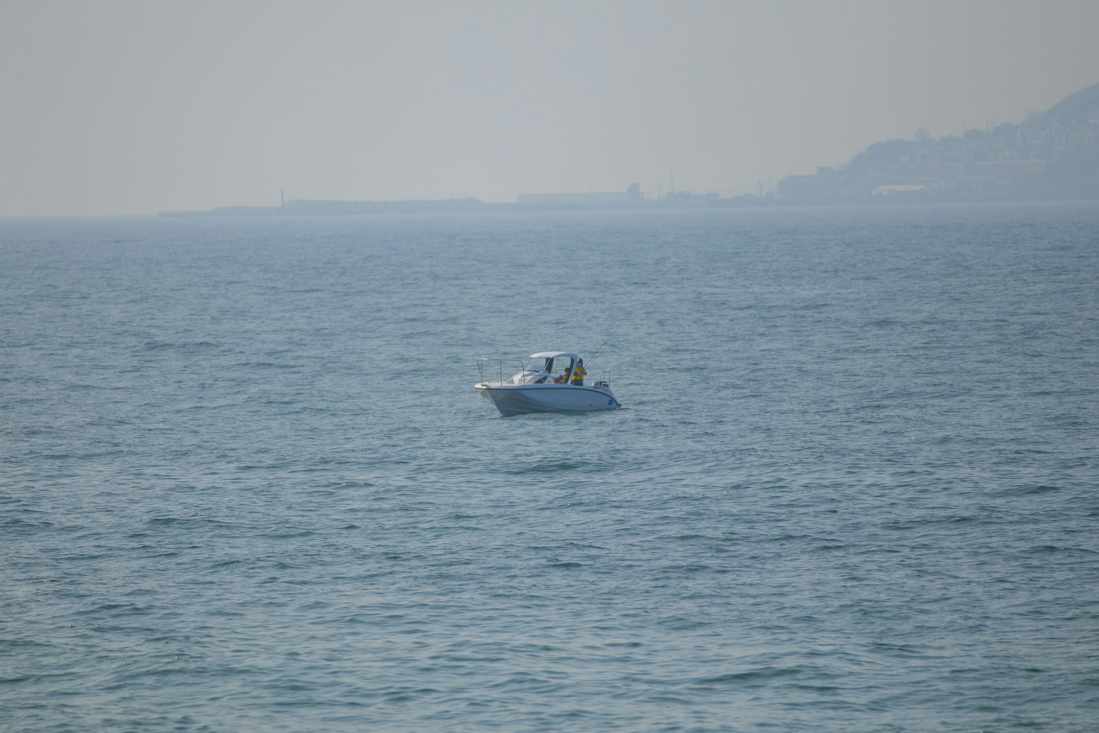 A small boat floating on the ocean with a hazy background