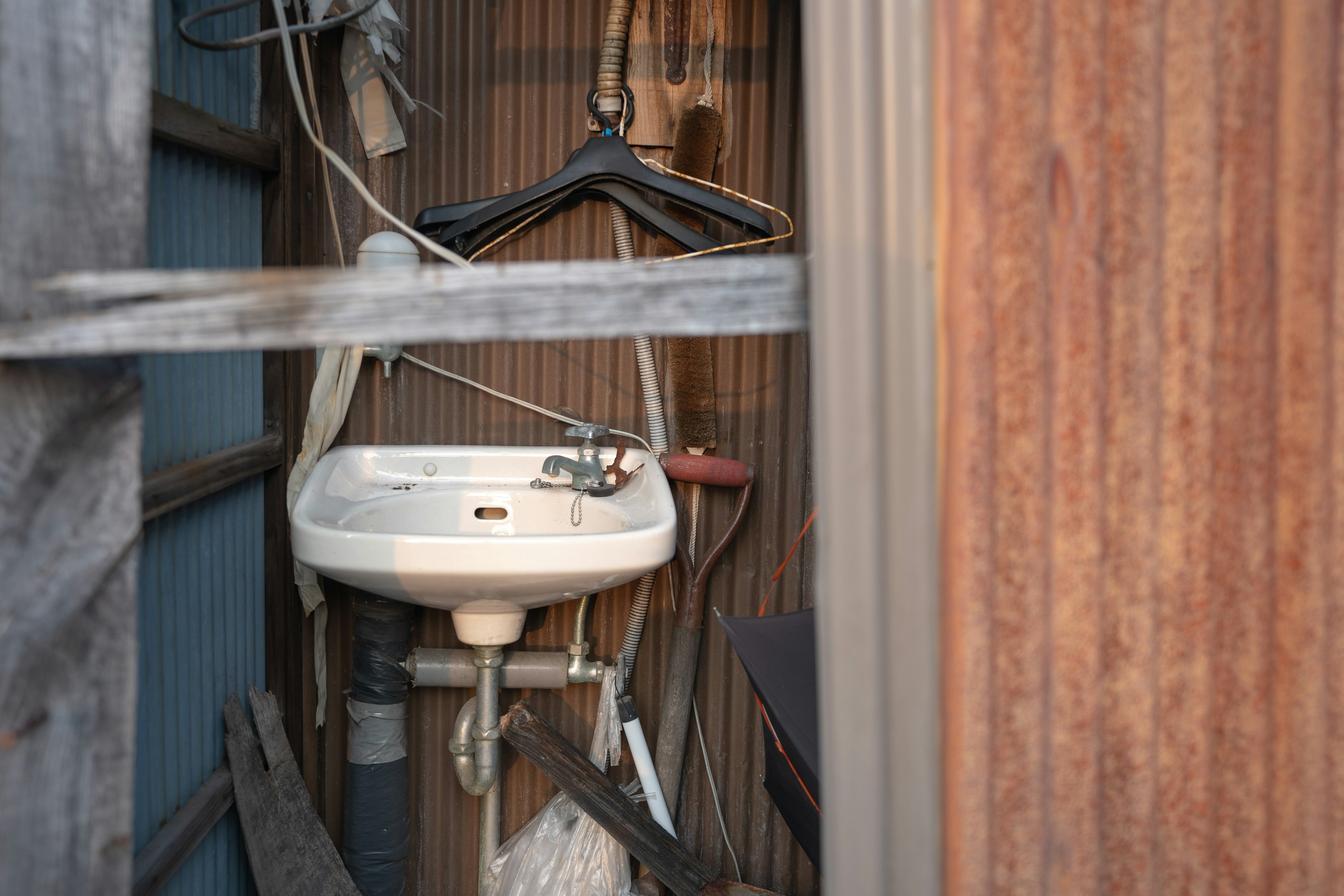 A narrow space featuring an old sink and a hanger