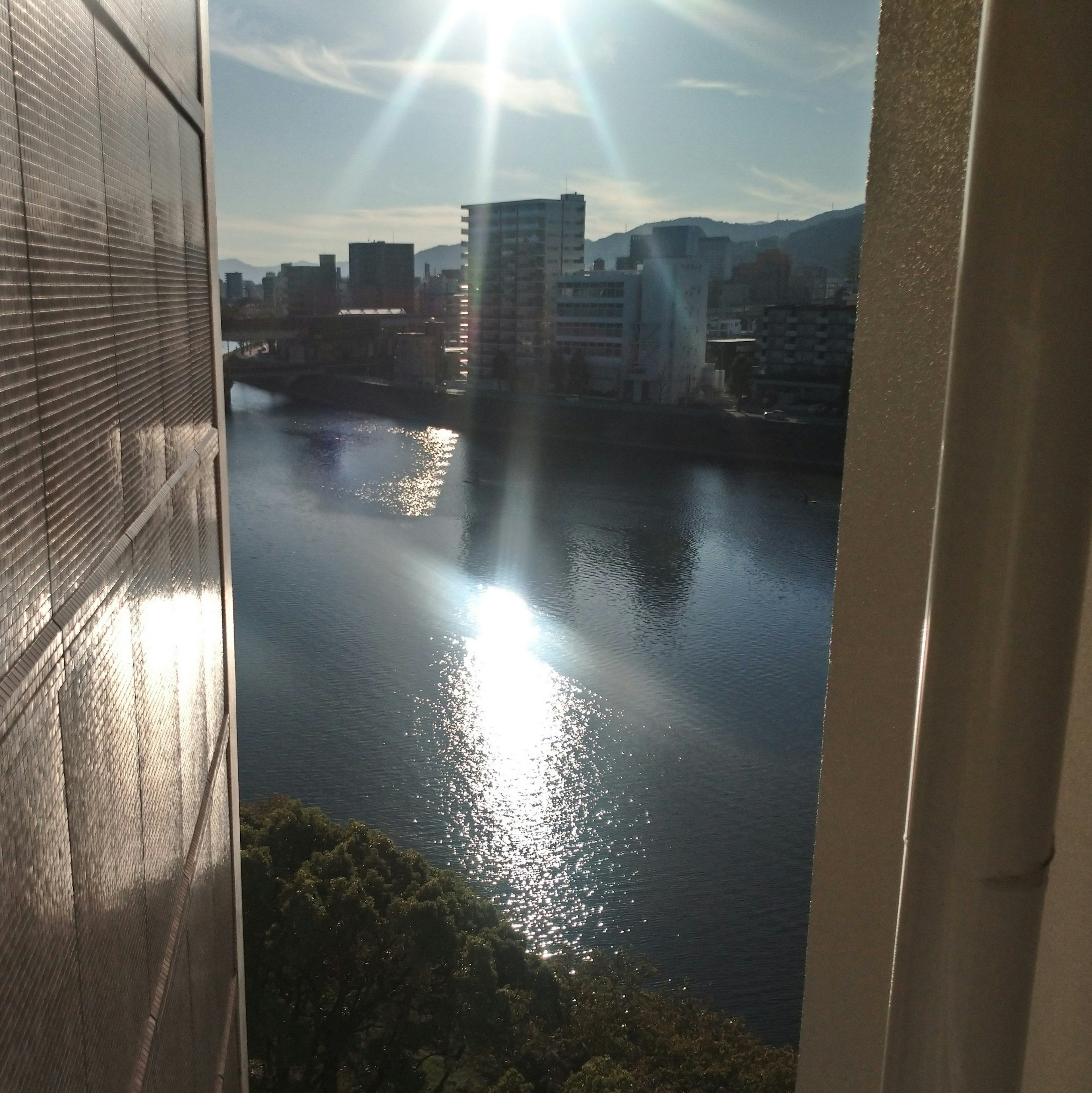 Vista di un fiume e del paesaggio urbano da una finestra con luce solare brillante che si riflette sull'acqua