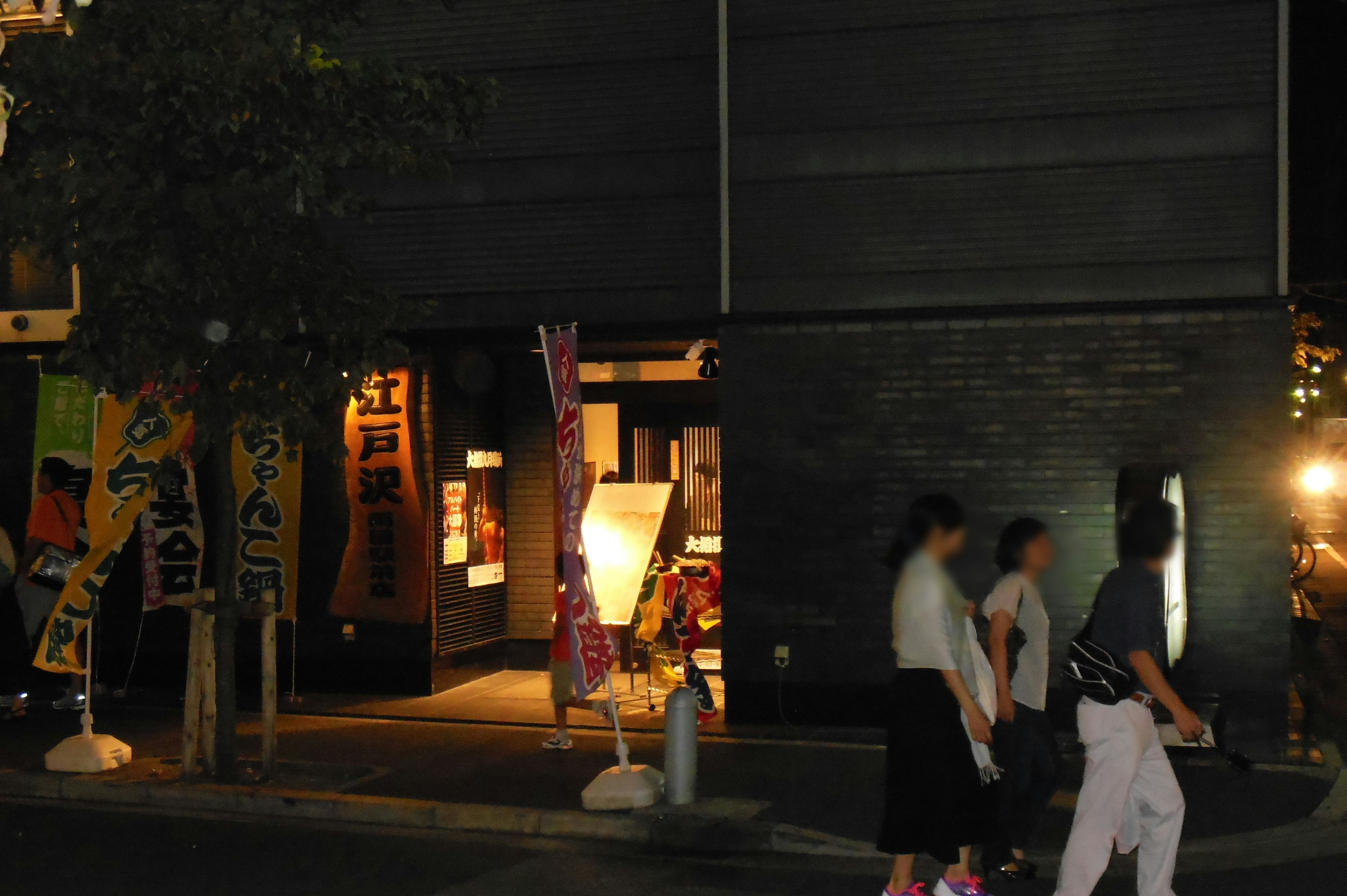 Entrance of a restaurant at night with pedestrians