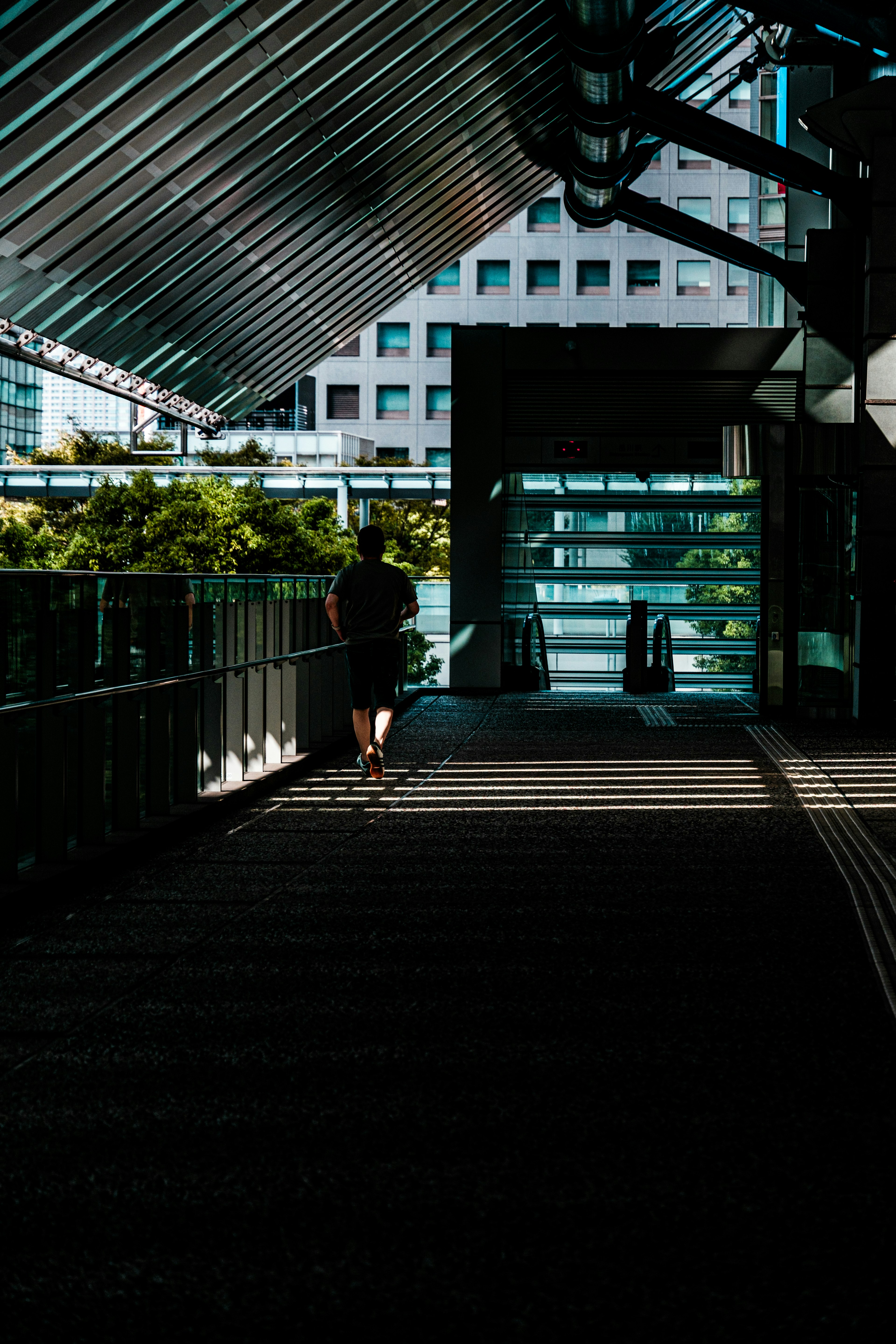 A person walking along a shaded walkway beside a modern building