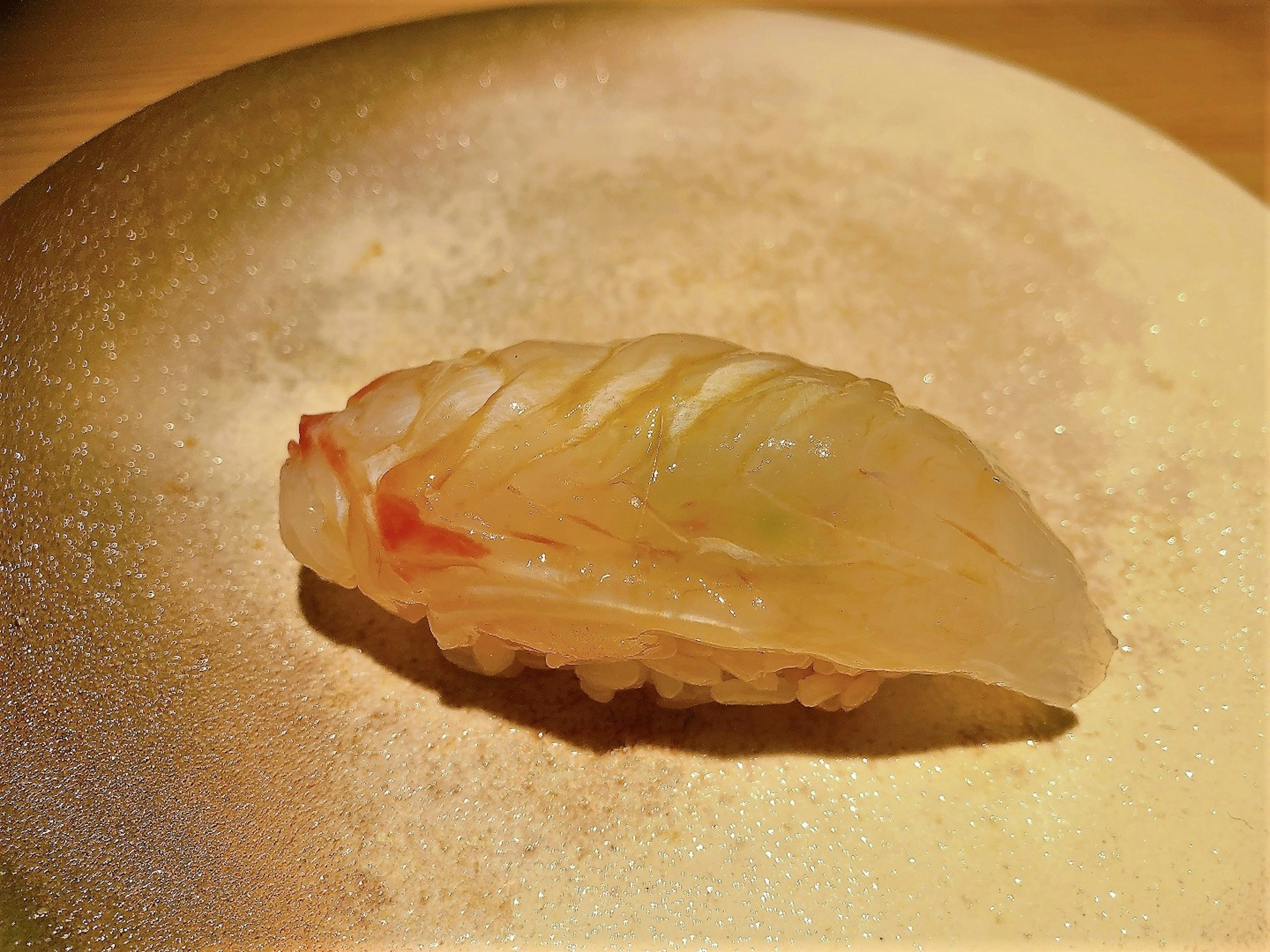 A vibrant sushi piece placed on a golden plate