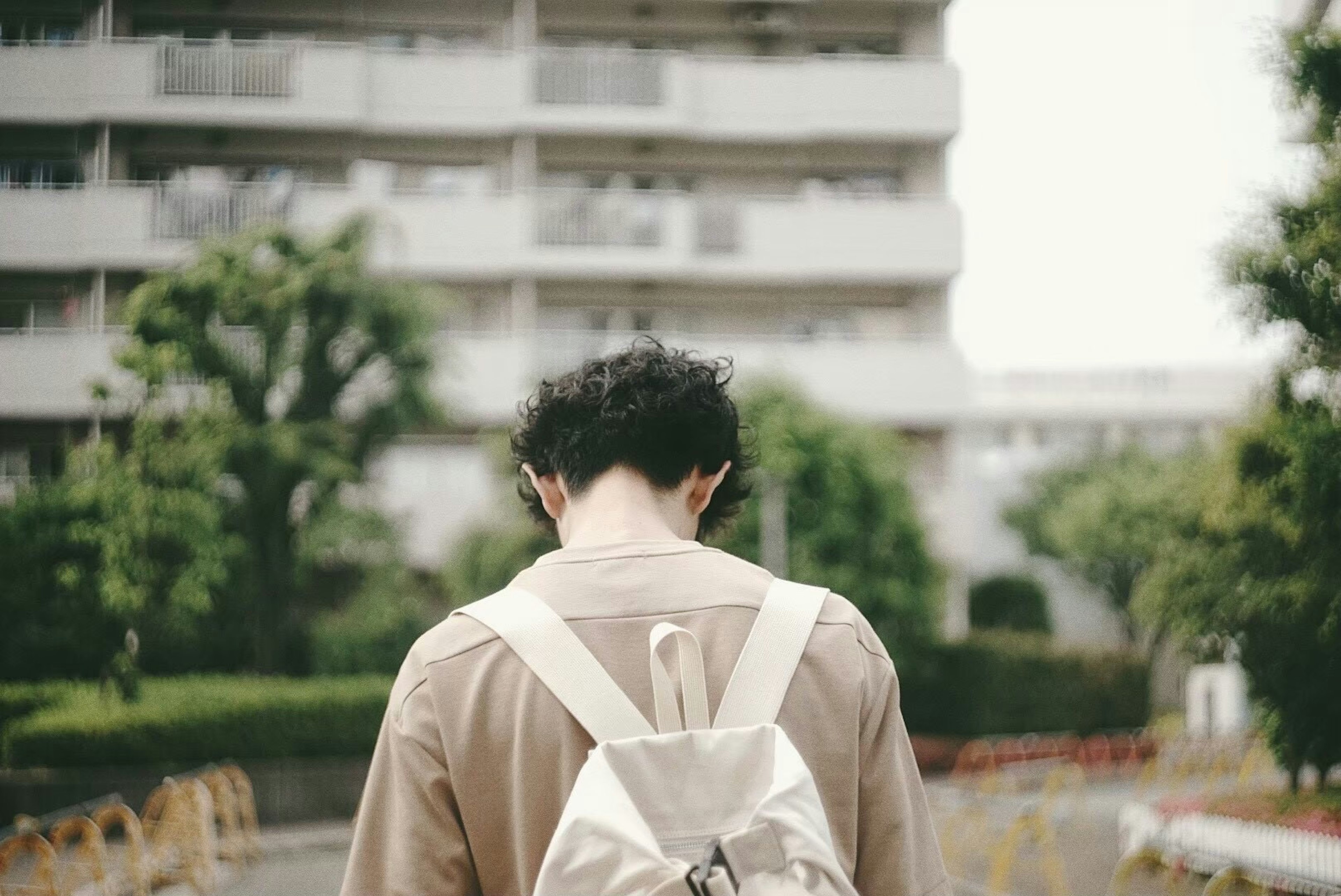 Joven caminando con una mochila en una zona residencial