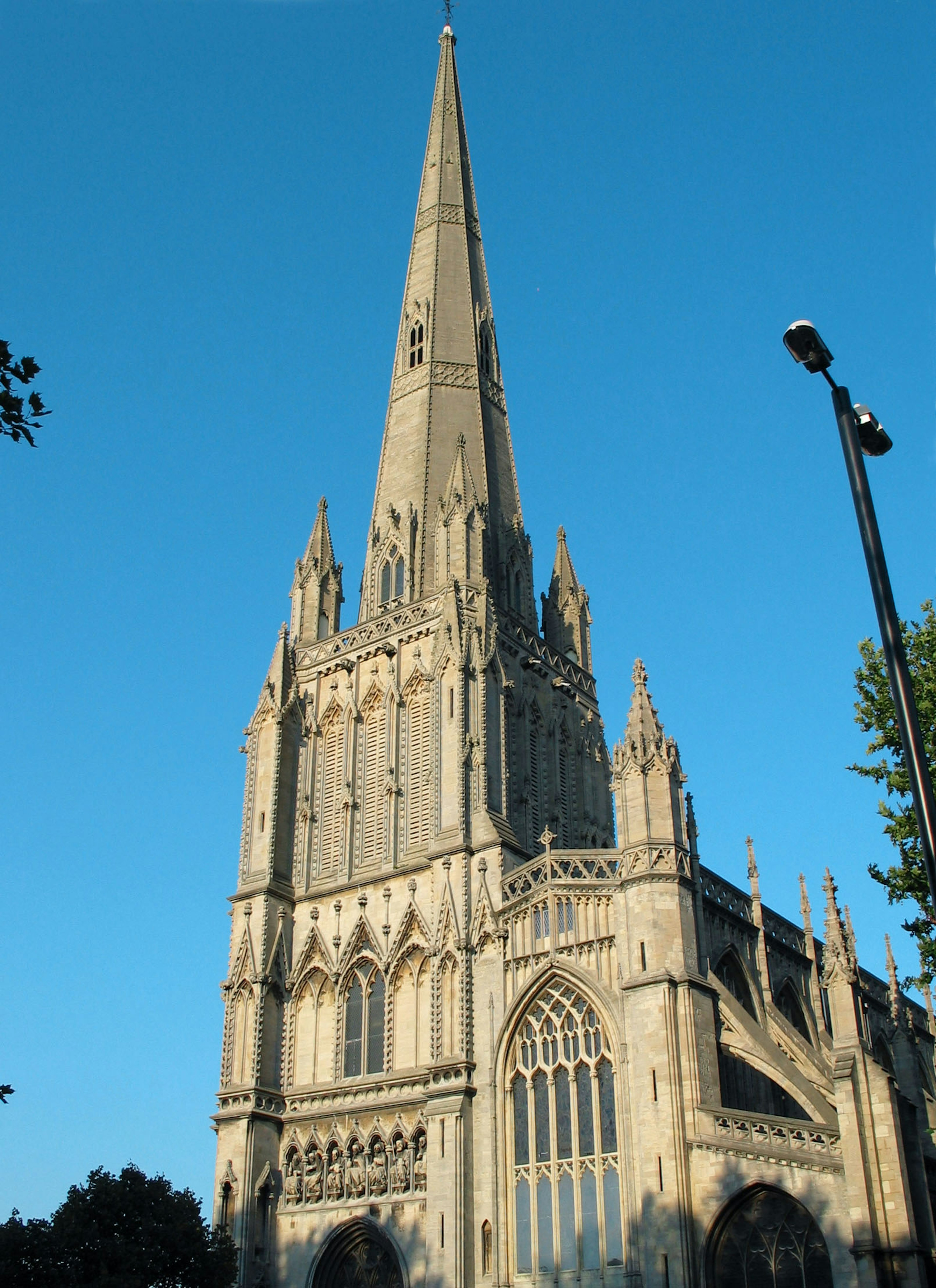 Stone church with a tall spire under a clear blue sky