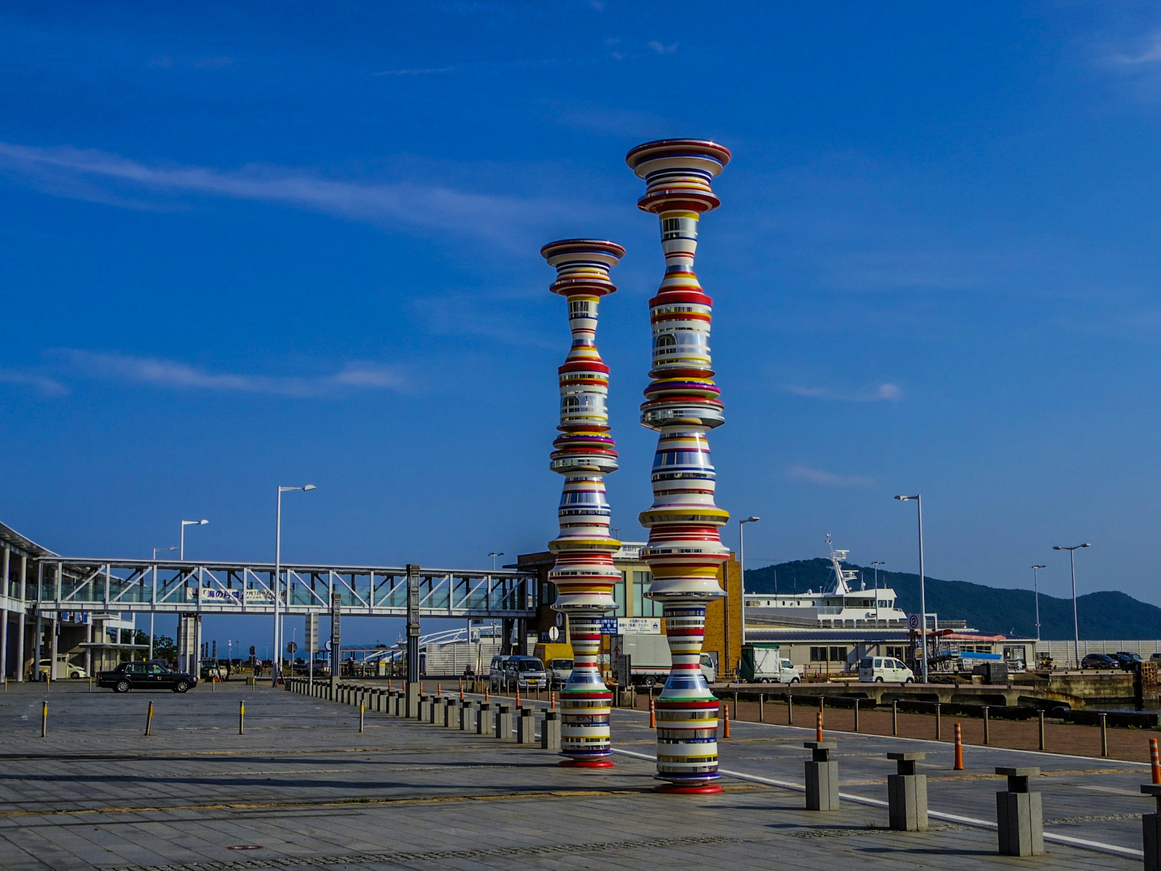 カラフルな円柱の彫刻が並ぶ港の風景