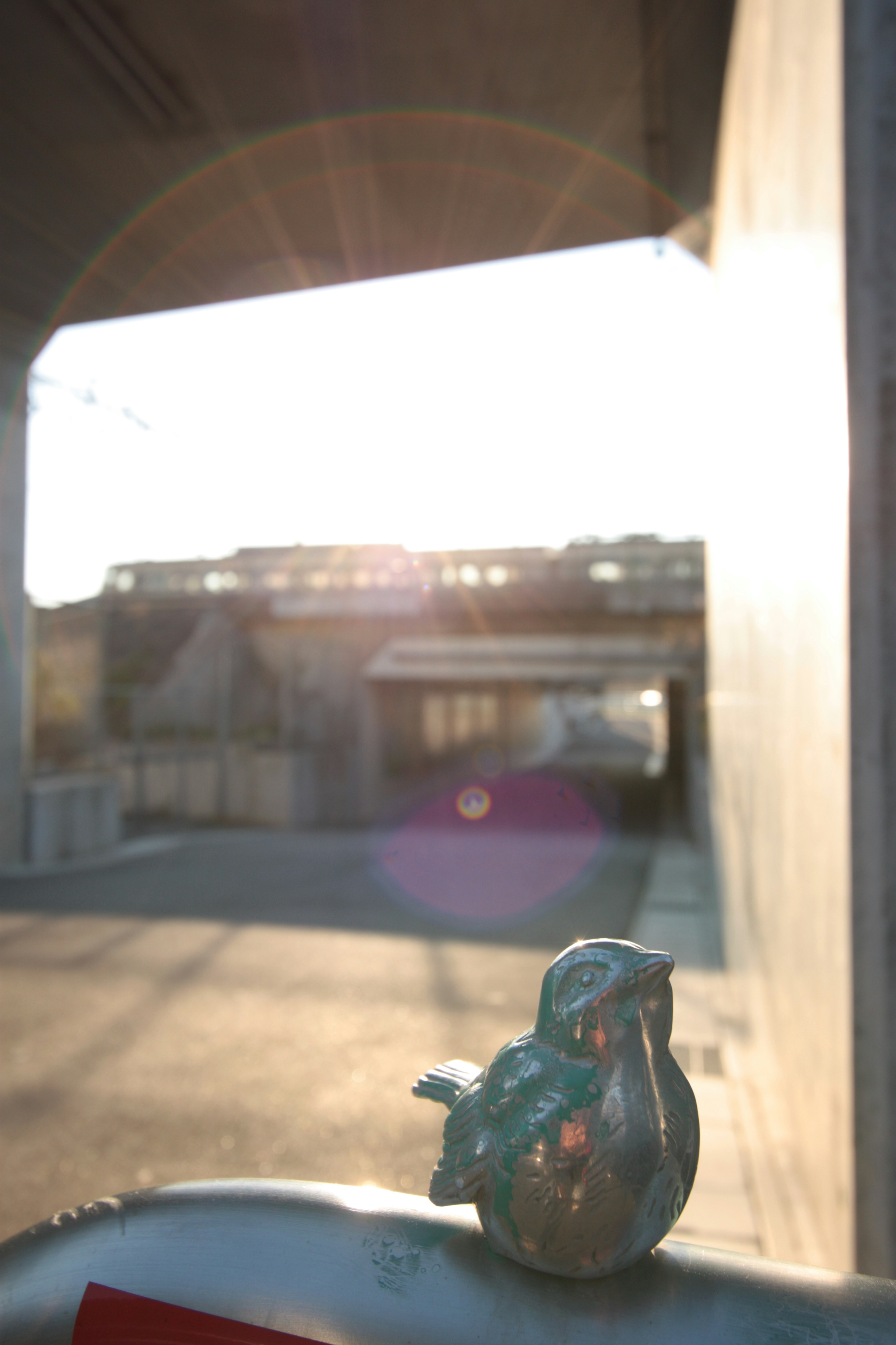 Figurita de pájaro turquesa frente a un túnel iluminado por el sol