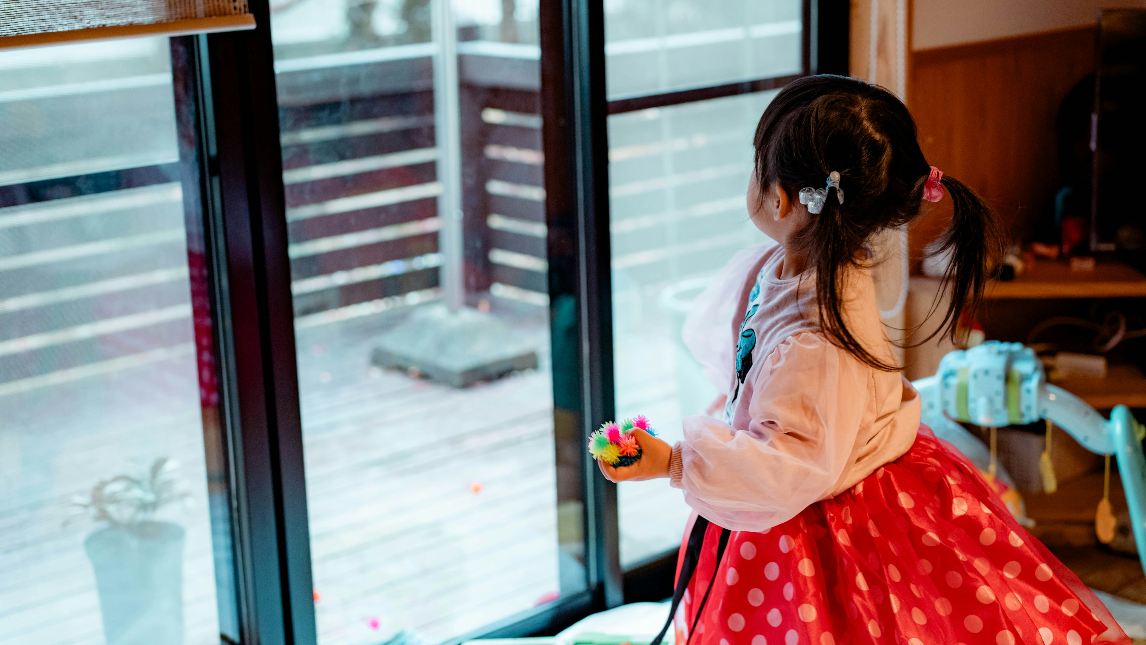 Girl in a red polka dot dress gazing out the window