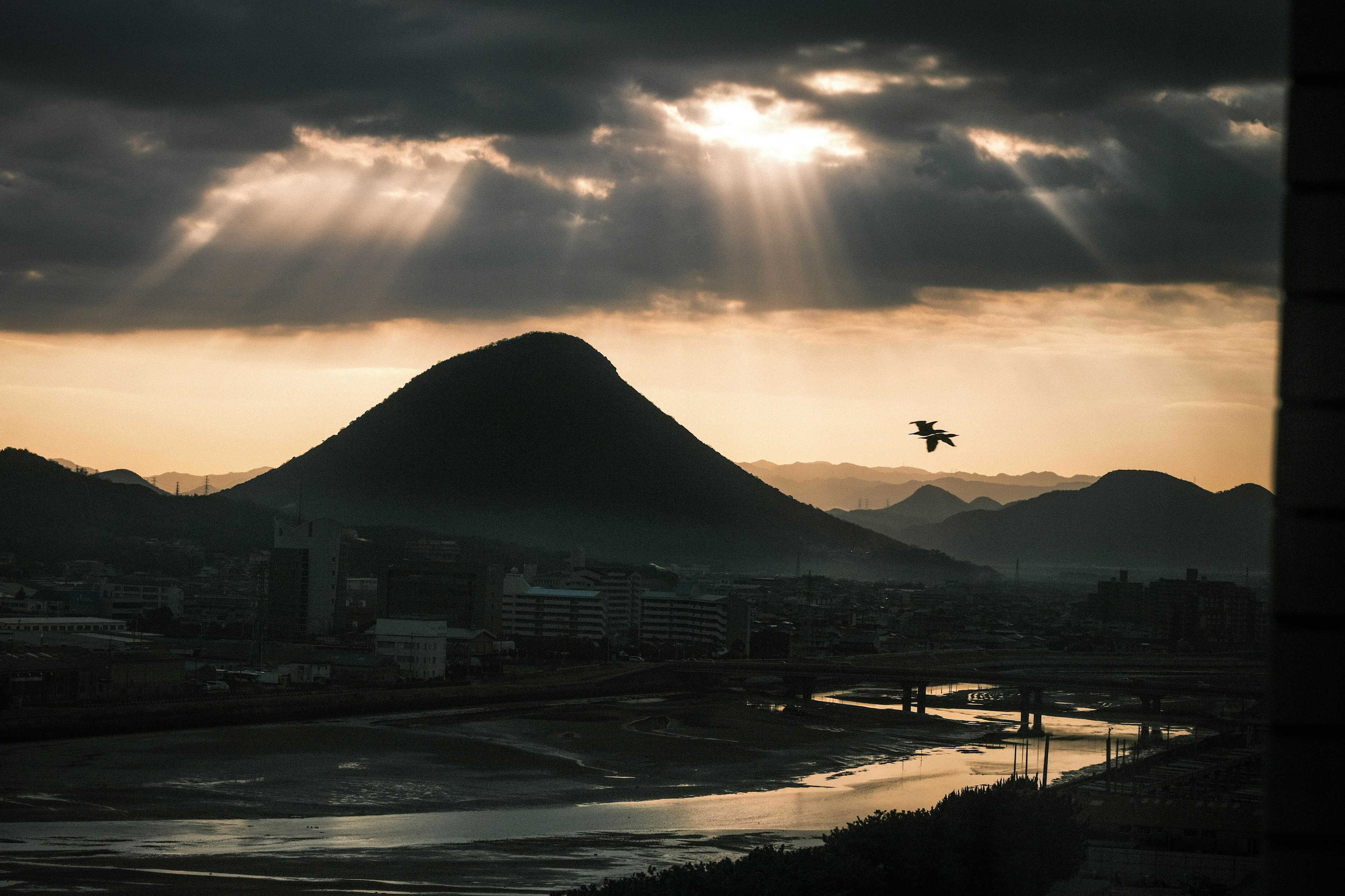 Silhouette d'une montagne sous des nuages dramatiques avec des rayons de soleil