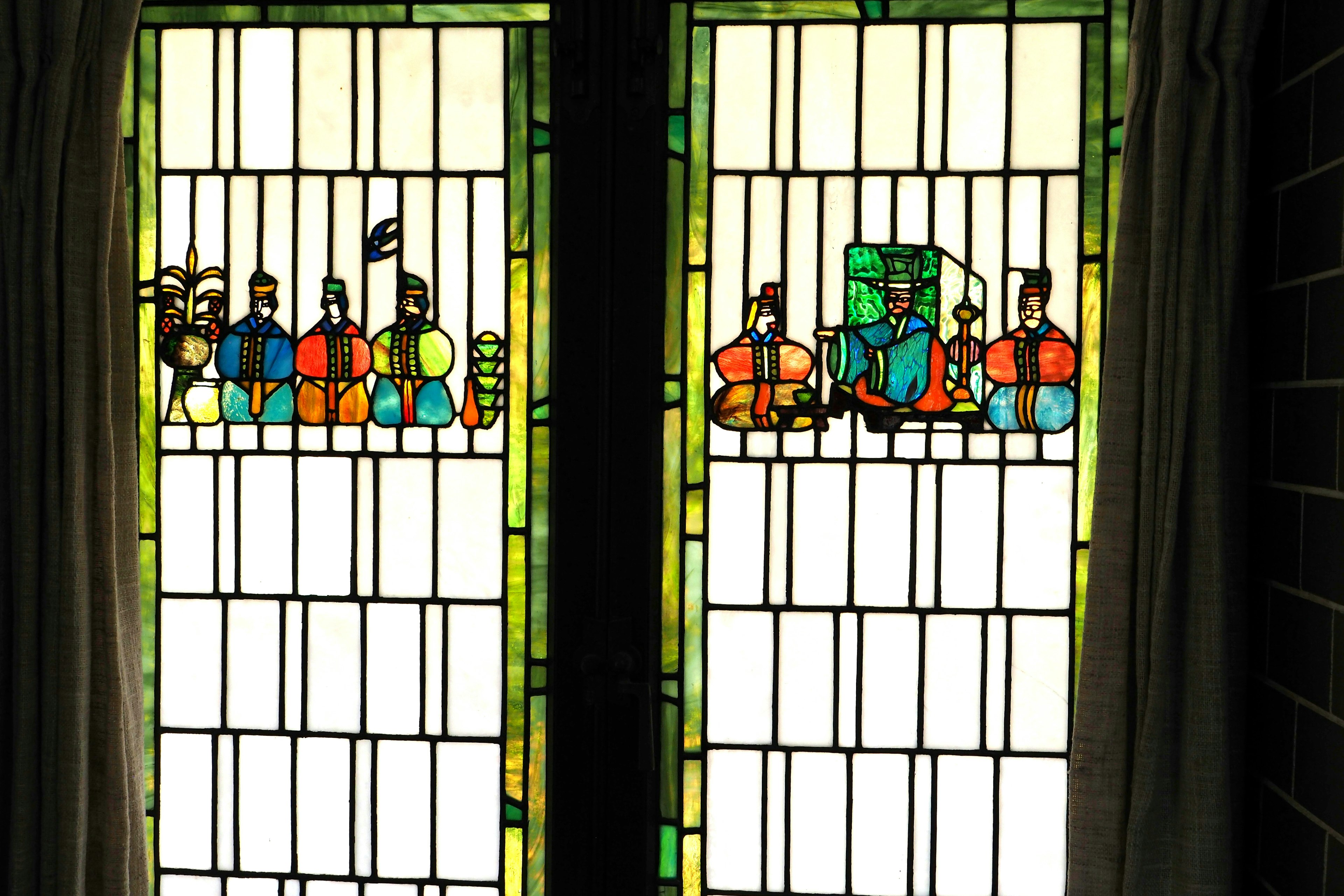 Ventana de vidrio colorido que representa escenas con figuras y objetos