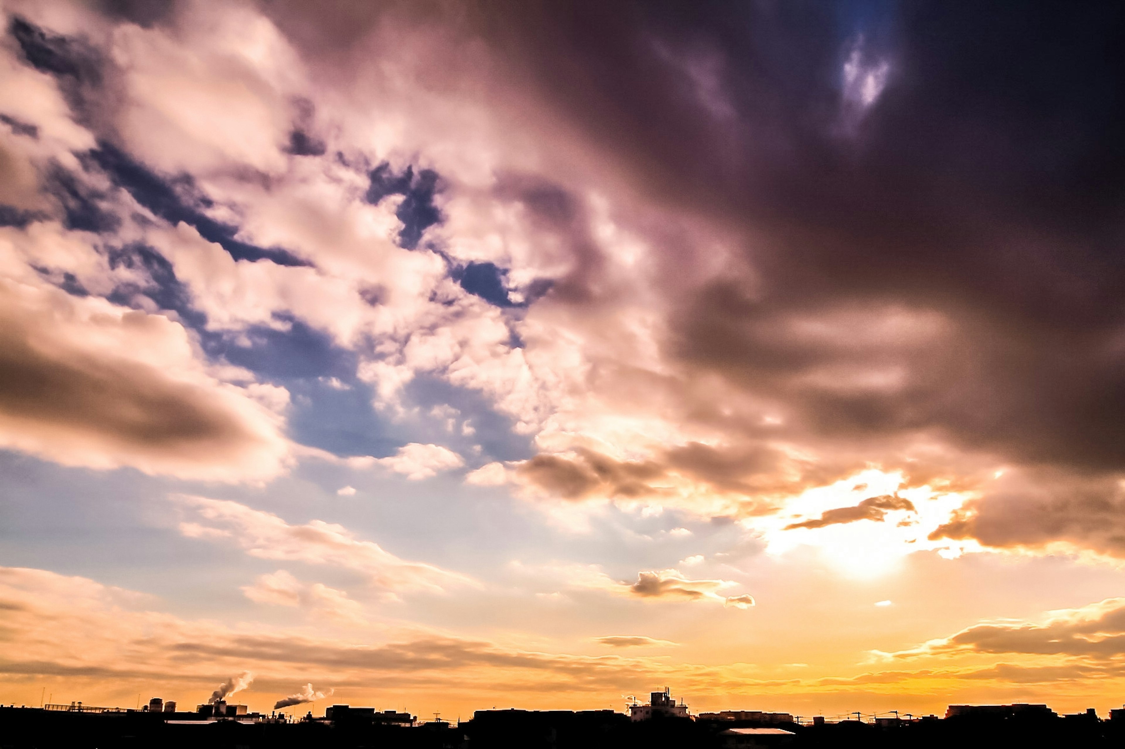 Langit senja dengan awan berwarna dan bangunan siluet