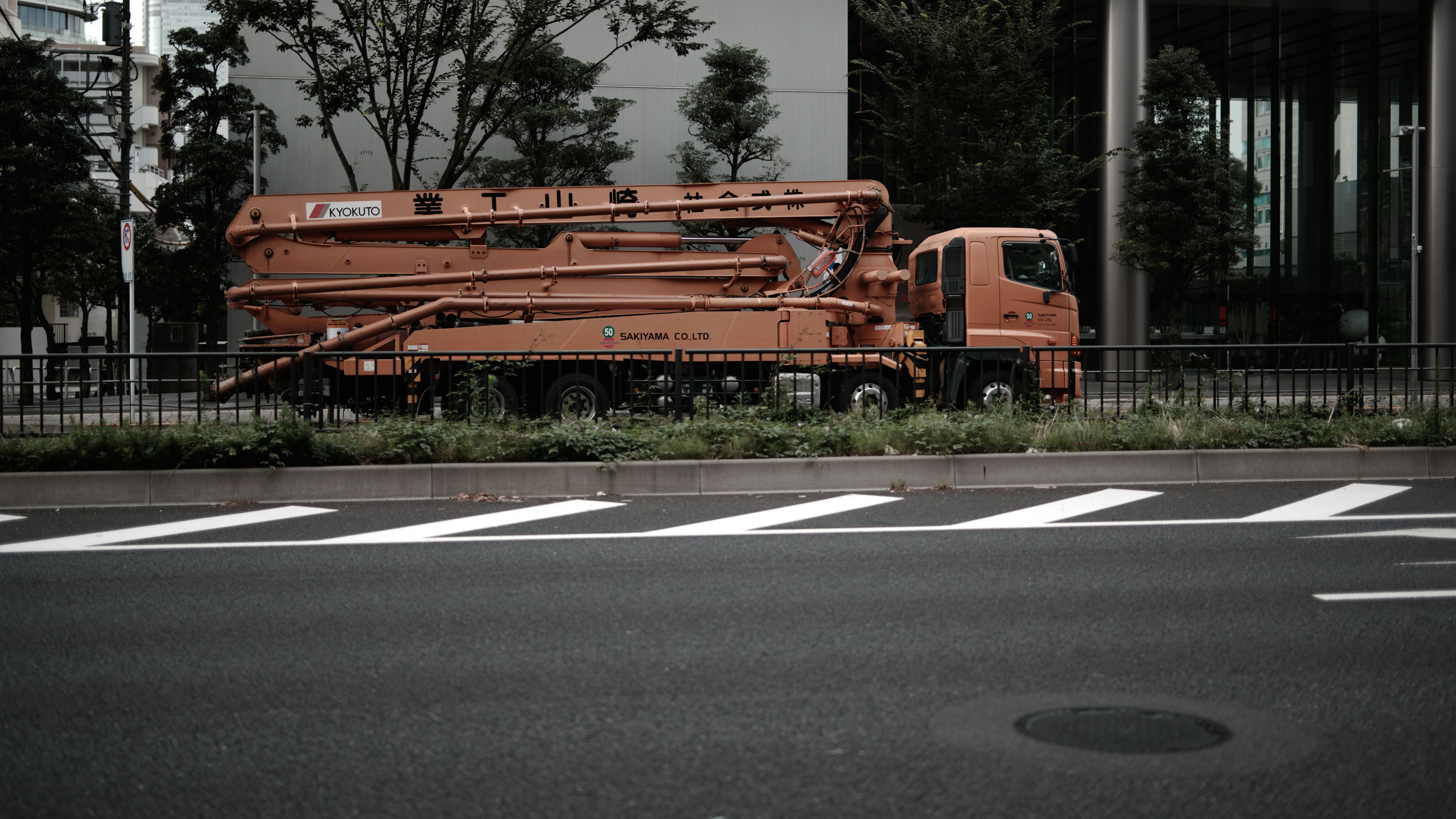 An orange crane truck parked beside the road in an urban setting