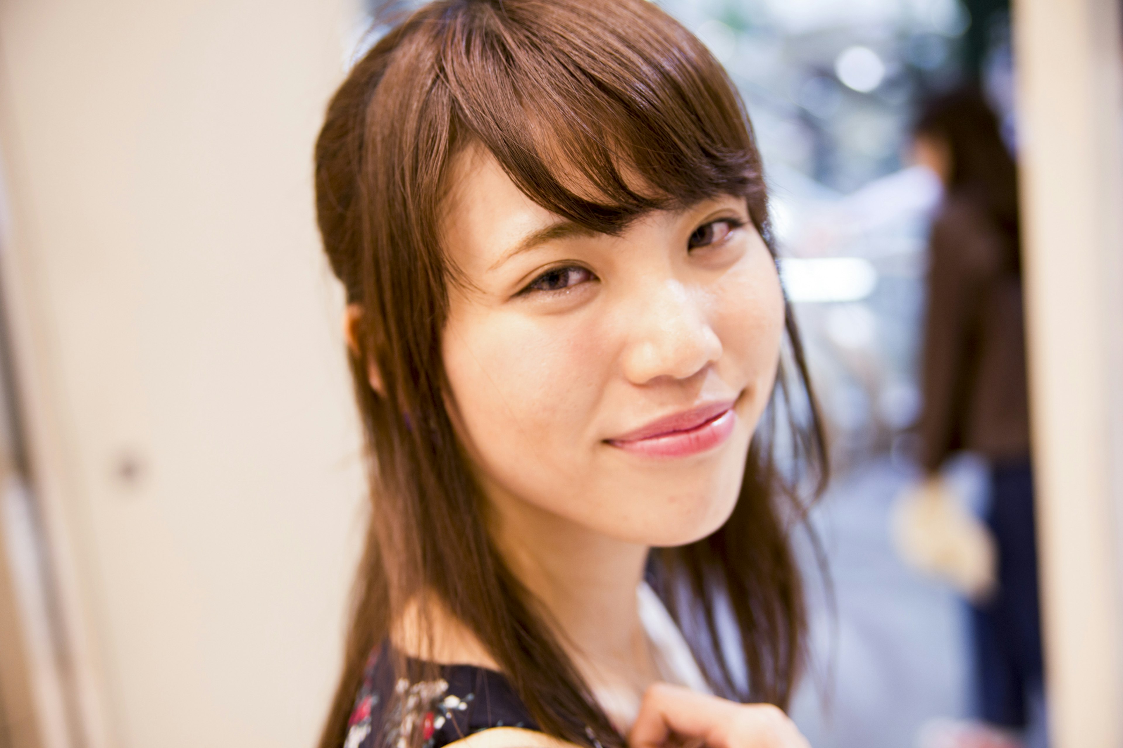 A woman smiling with long brown hair blurred city background