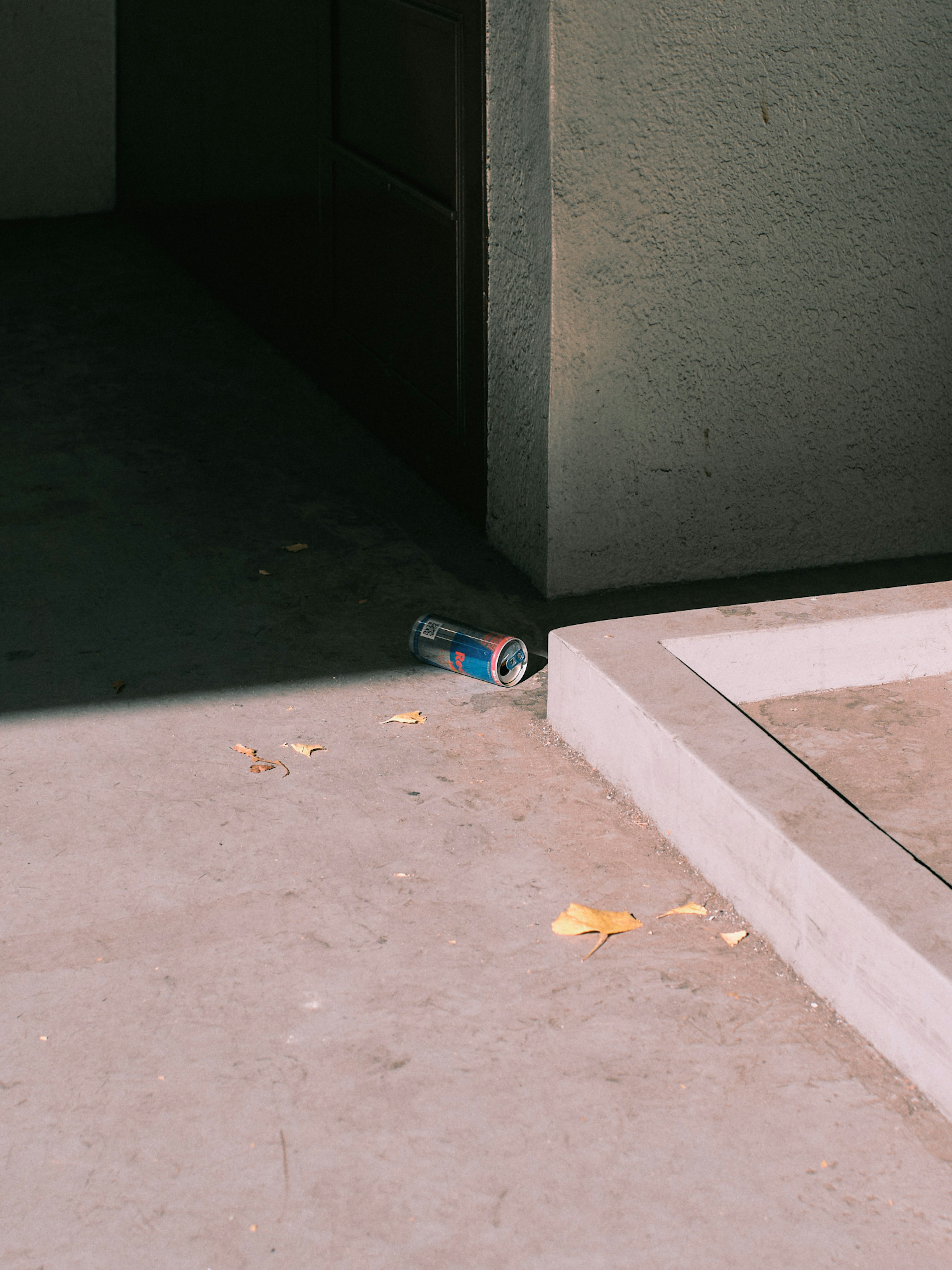 A discarded can near a wall corner with contrasting shadows